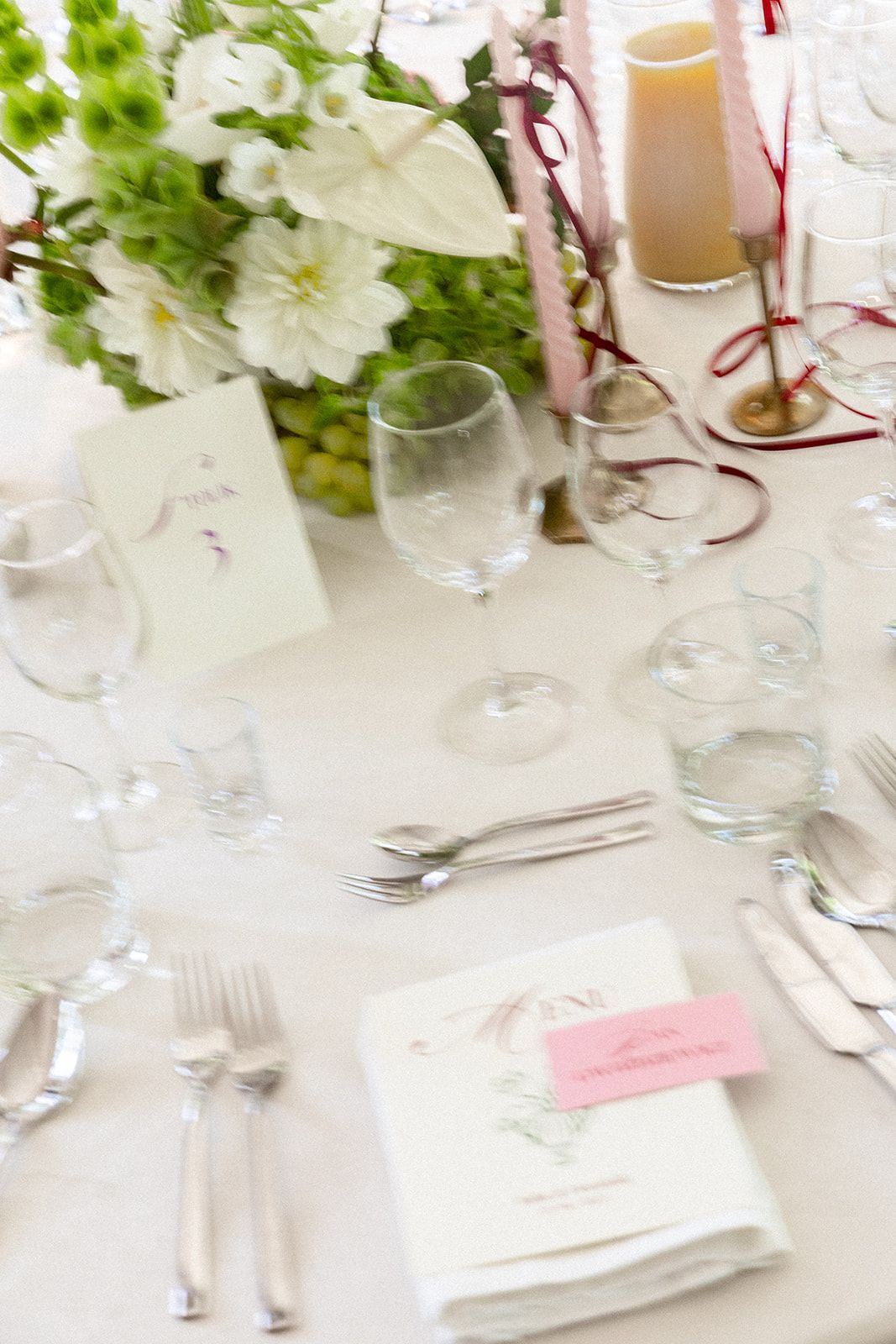 Elegant white floral centerpiece on a formal dining table with place settings and glassware for a special event.