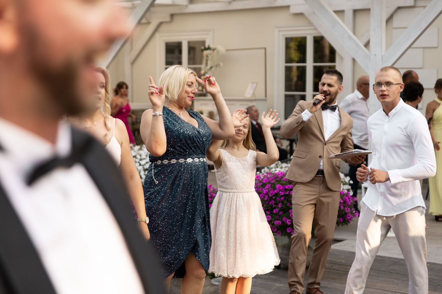 Wedding guests dance and celebrate together on an outdoor patio during a reception party.