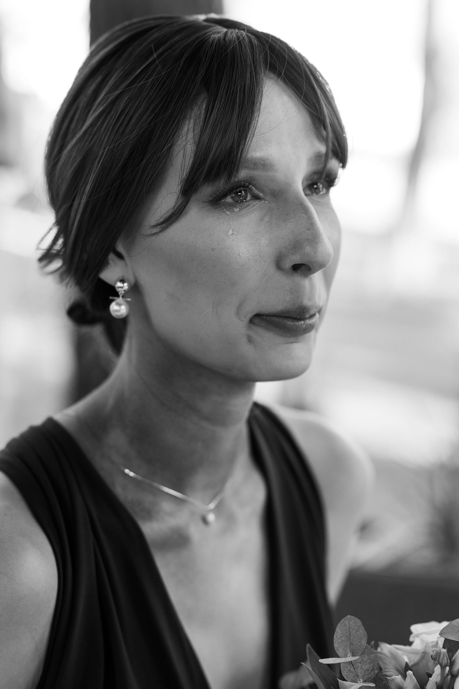 Black and white portrait photograph showing a contemplative expression in soft lighting, wearing pearl earrings and necklace.