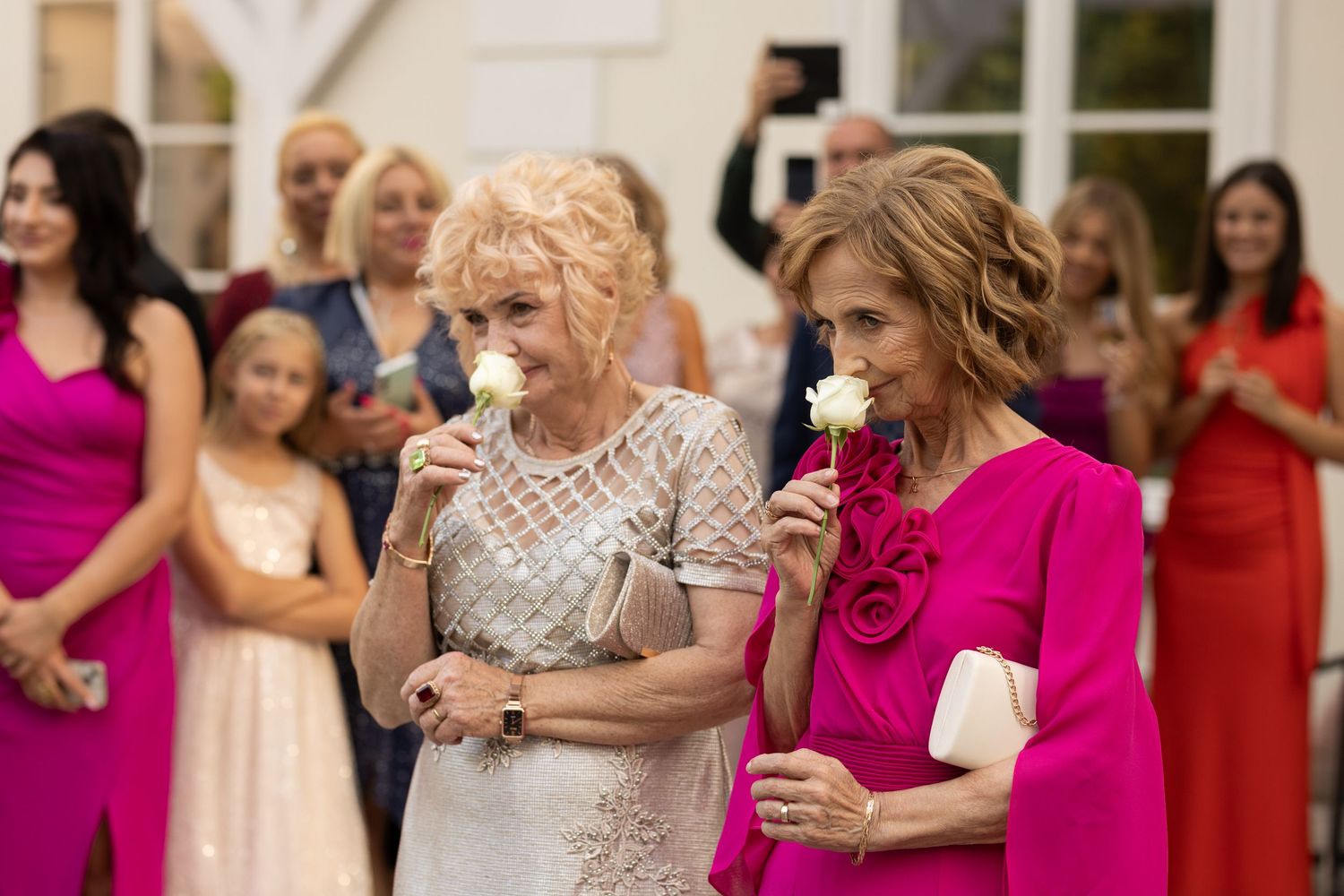 A wedding celebration with bridesmaids in bright pink dresses dancing and socializing at an indoor reception.