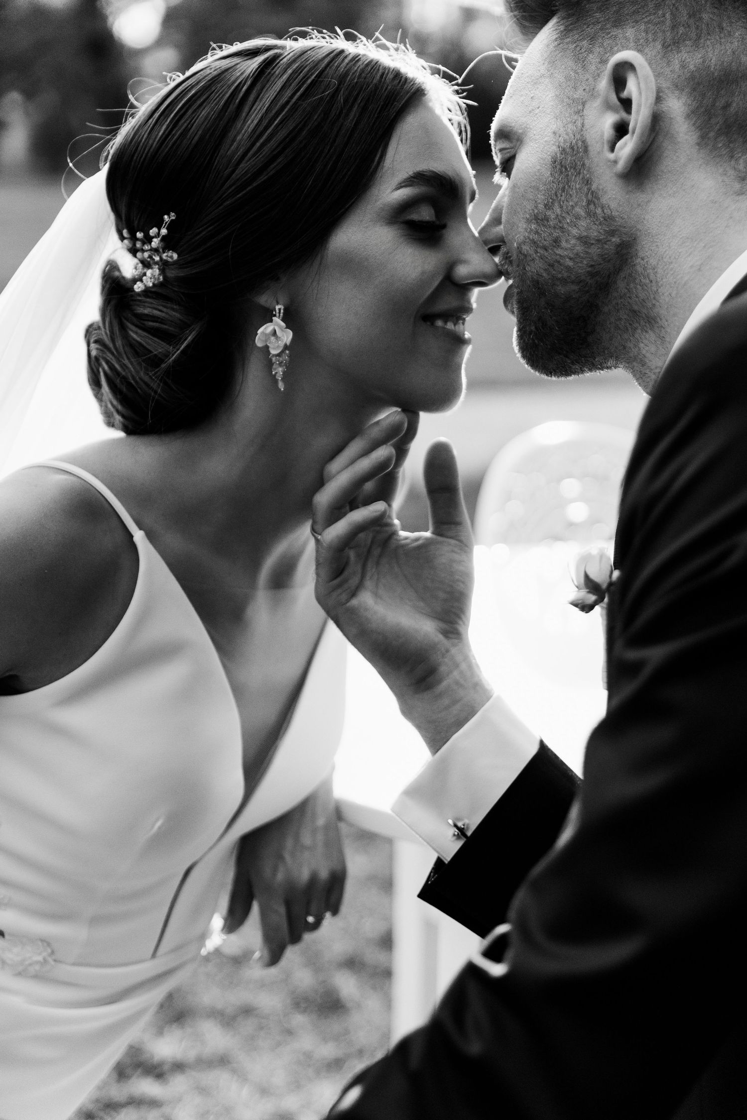 Black and white close-up of tender moment between bride and groom with ornate hair accessories.