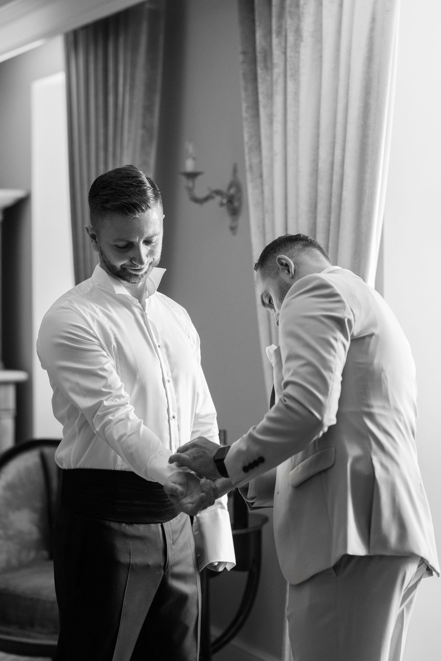 Black and white photo sequence showing two people in formal attire helping each other get dressed and adjust clothing.