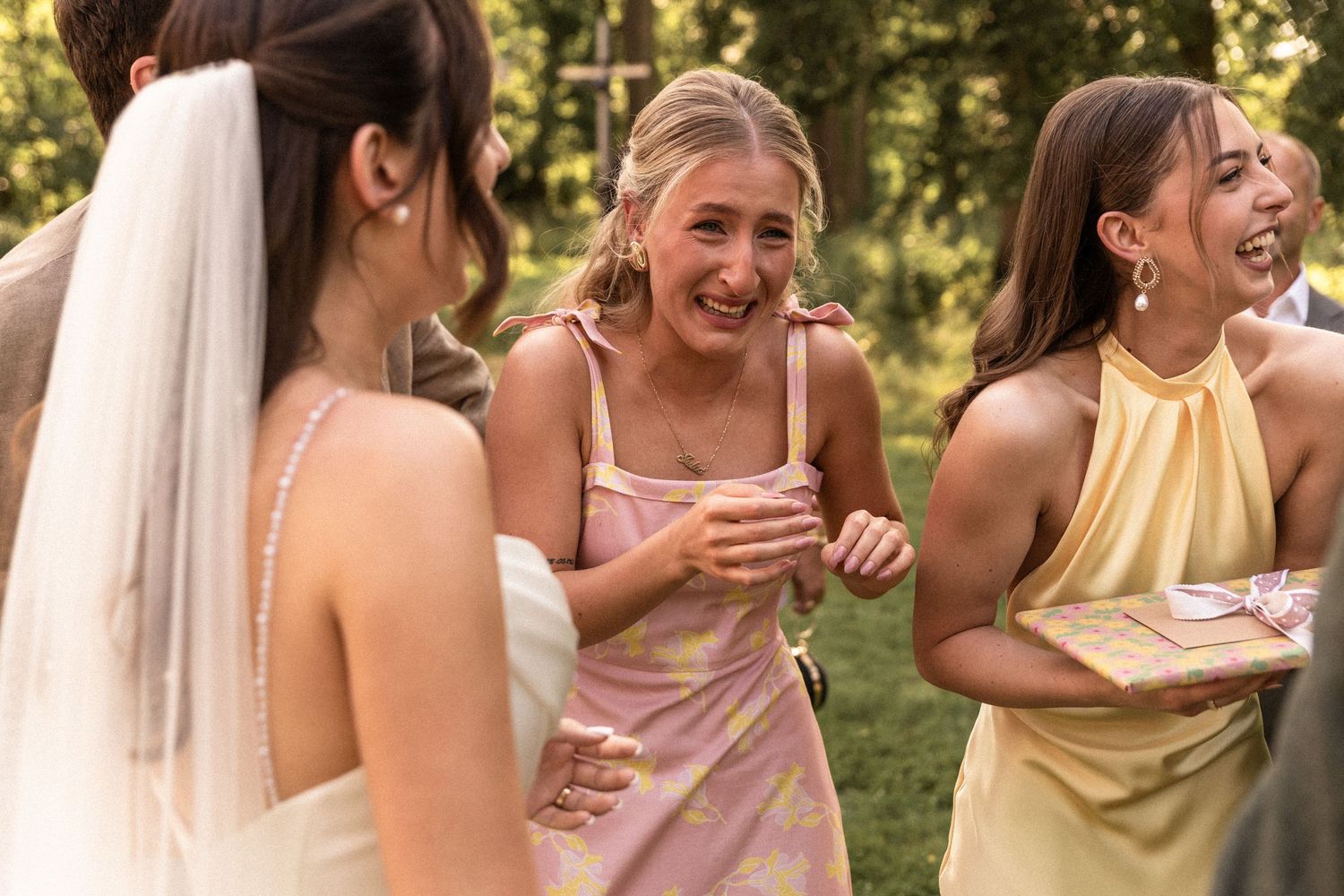 A group of bridesmaids in yellow dresses laugh and smile together during an outdoor wedding celebration.