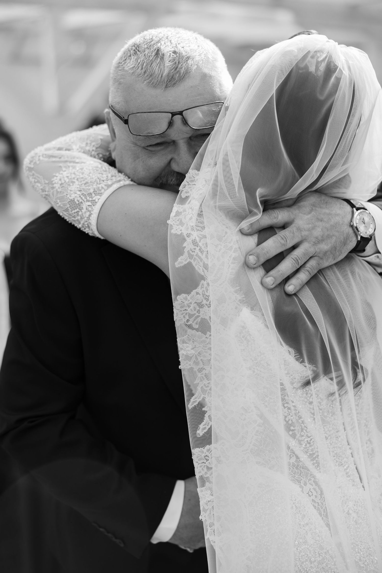 Black and white photo of a father embracing his bride daughter on her wedding day, both sharing an emotional moment.