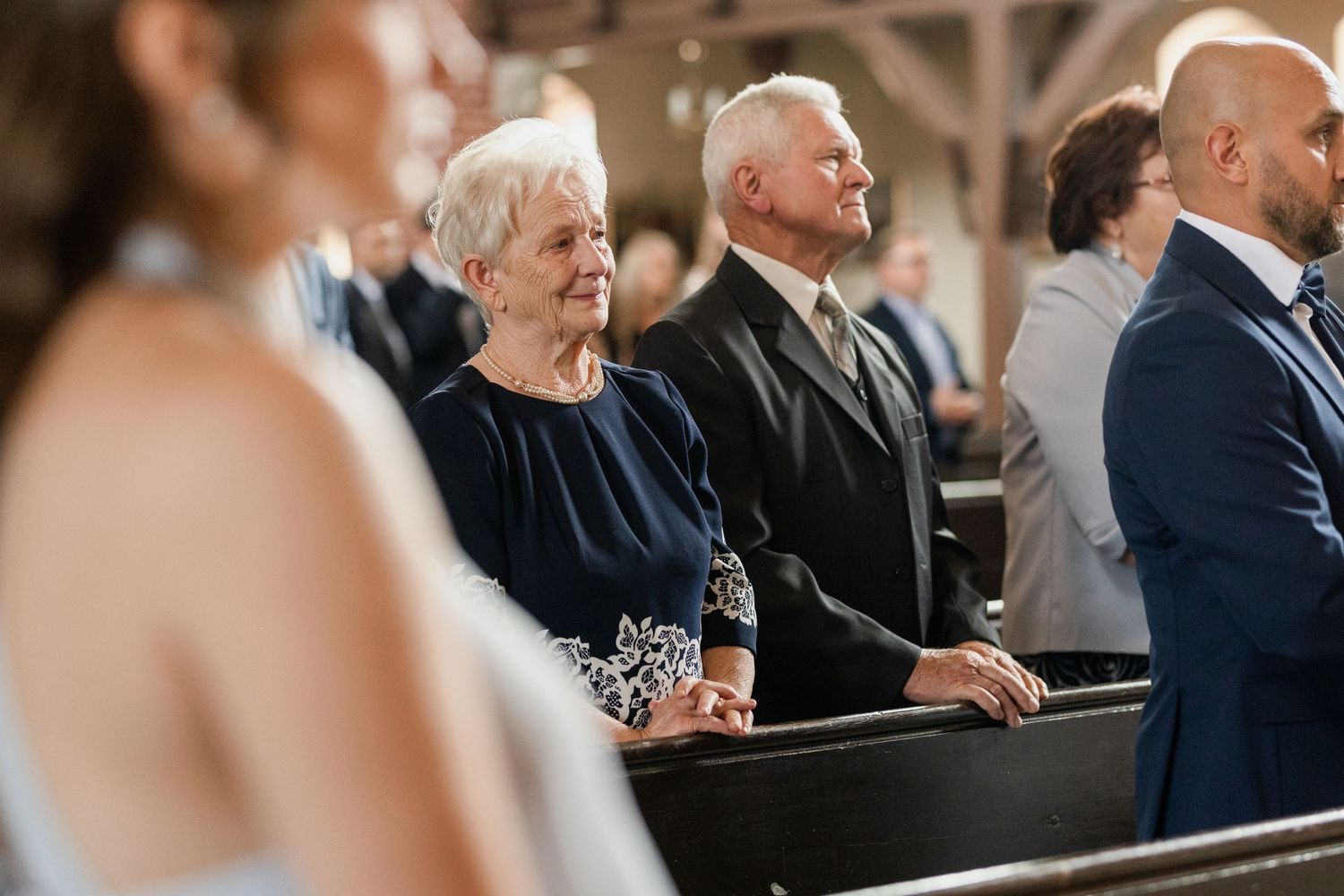 Wedding guests sit in rows during a ceremony, with soft lighting creating an intimate atmosphere.