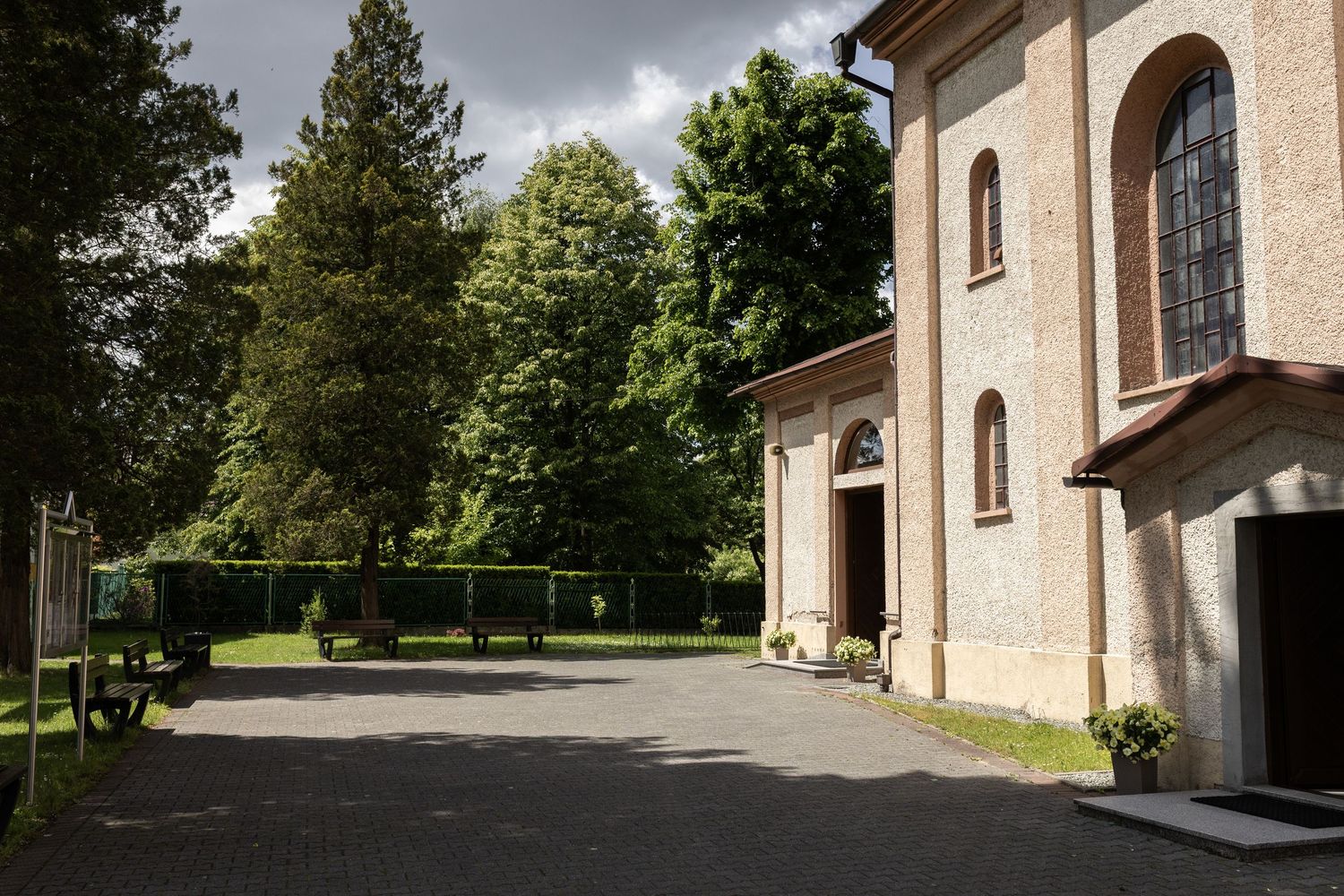 Exterior view of a classic church building with arched doorway and windows surrounded by lush green trees.