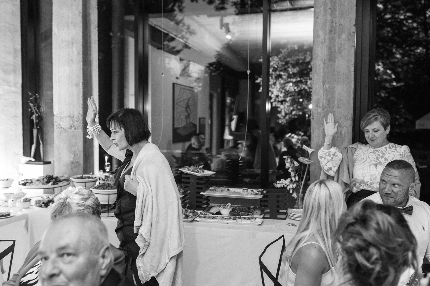 A black and white photo captures wedding party members in a candid moment outside a building.