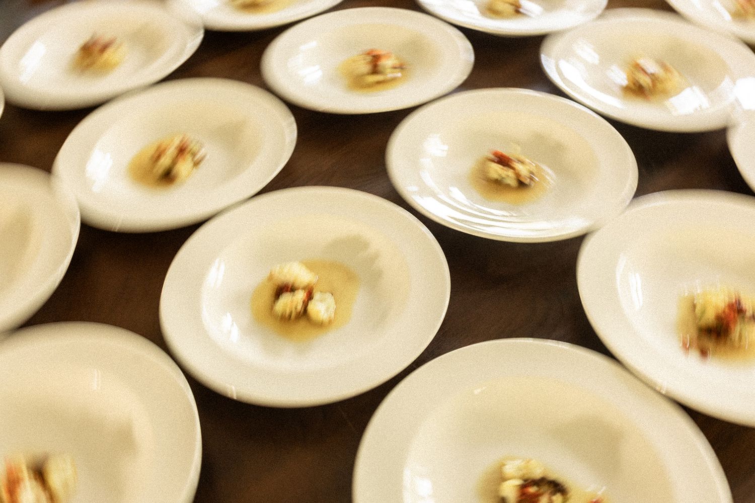 White ceramic plates with roasted nuts arranged in neat rows on a dark surface create an elegant dining presentation.