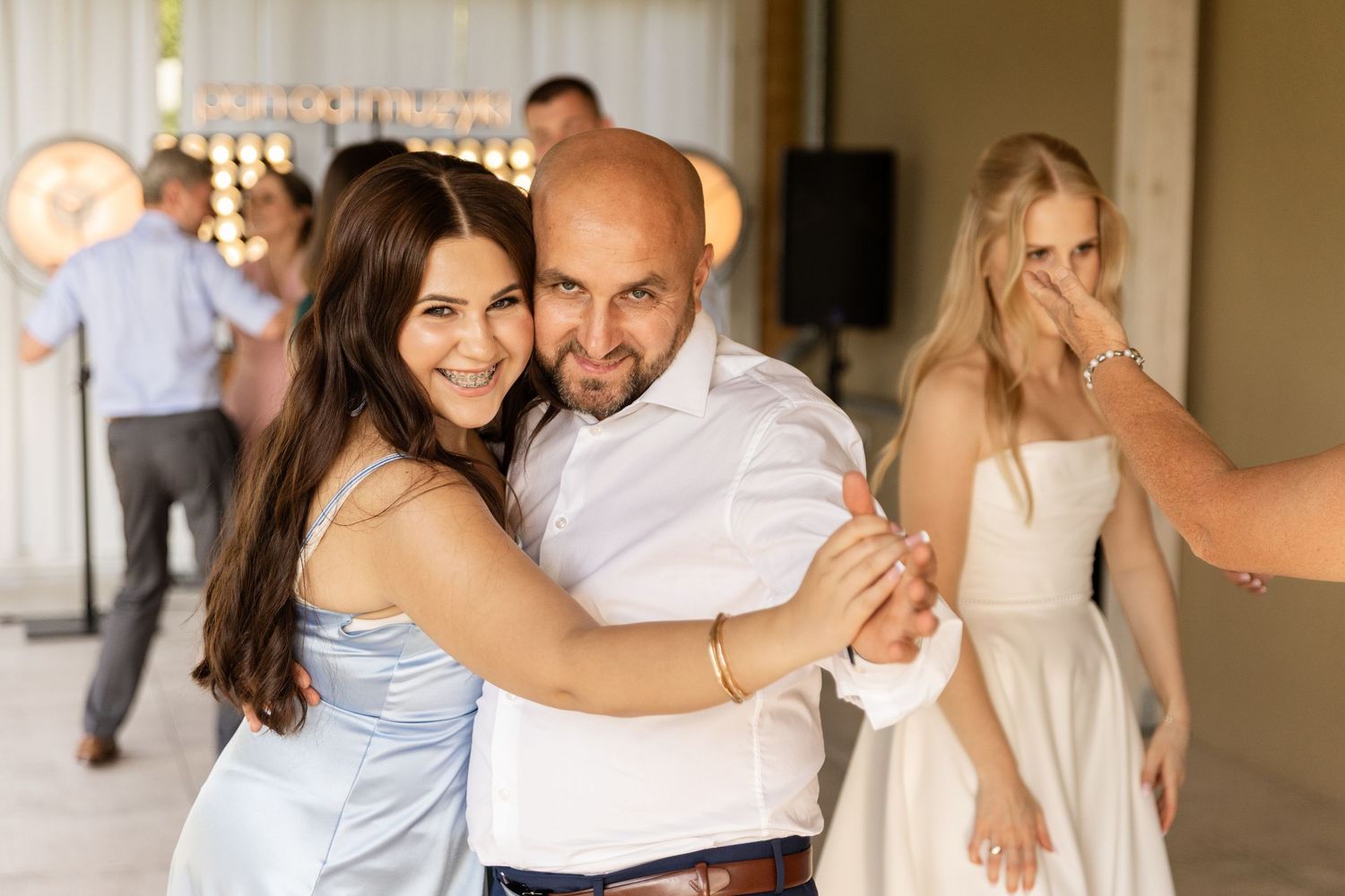 Elegant wedding couple dances together surrounded by guests at a reception celebration.