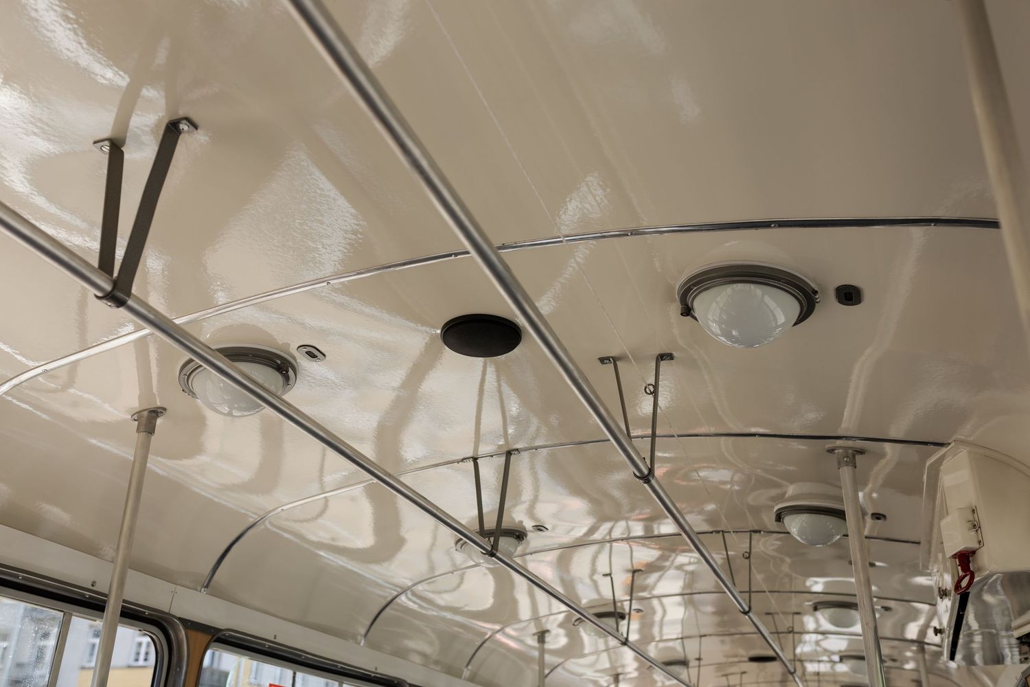 Vintage bus ceiling interior showing white painted metal with circular lights and support bars mounted along its length.