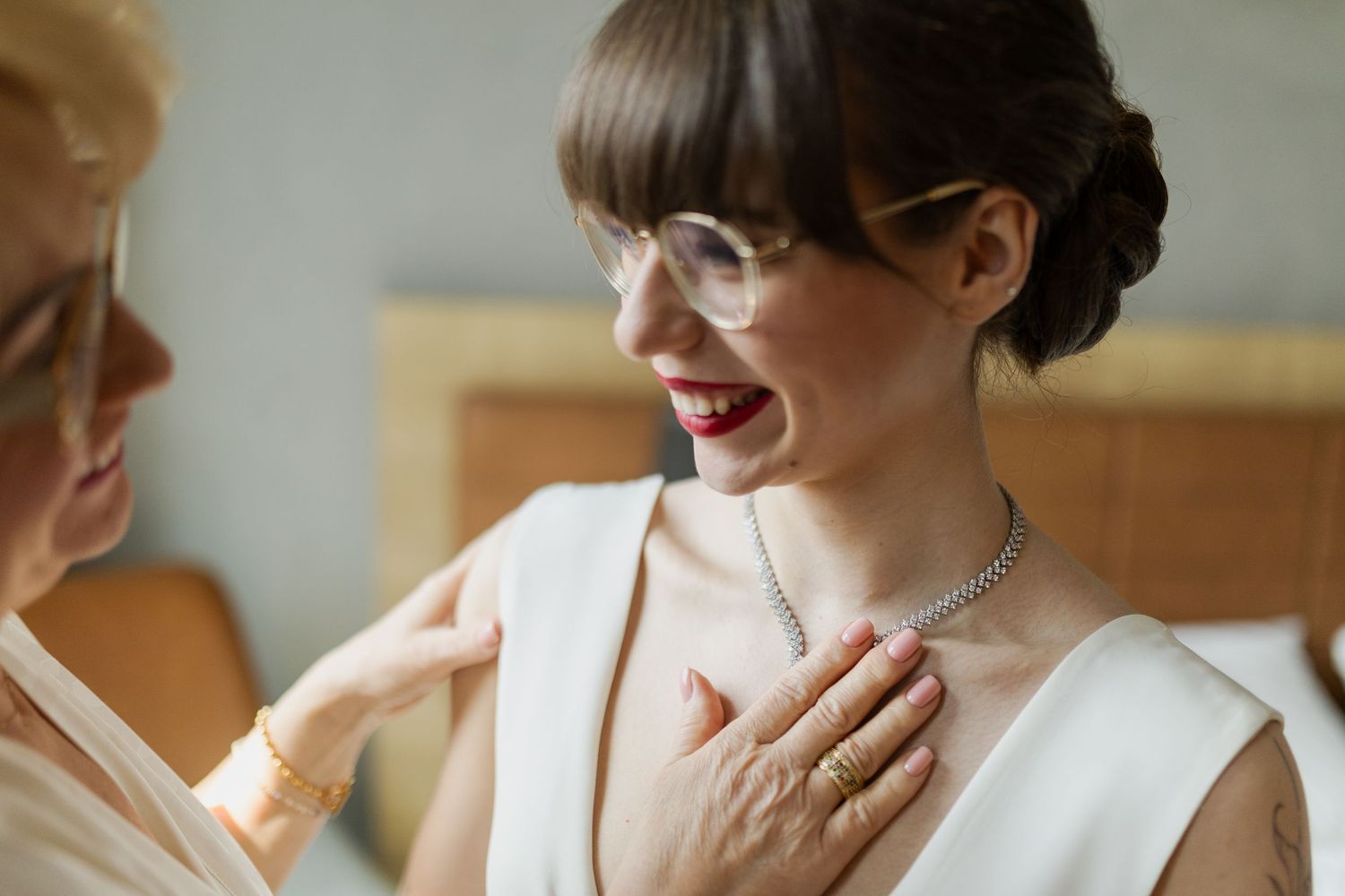 An emotional moment between two people during what appears to be a bridal preparation, with a focus on a white dress.