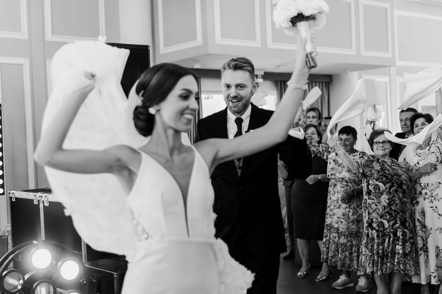 A joyful celebration on the dance floor at a black and white wedding reception as guests cheer in the background.