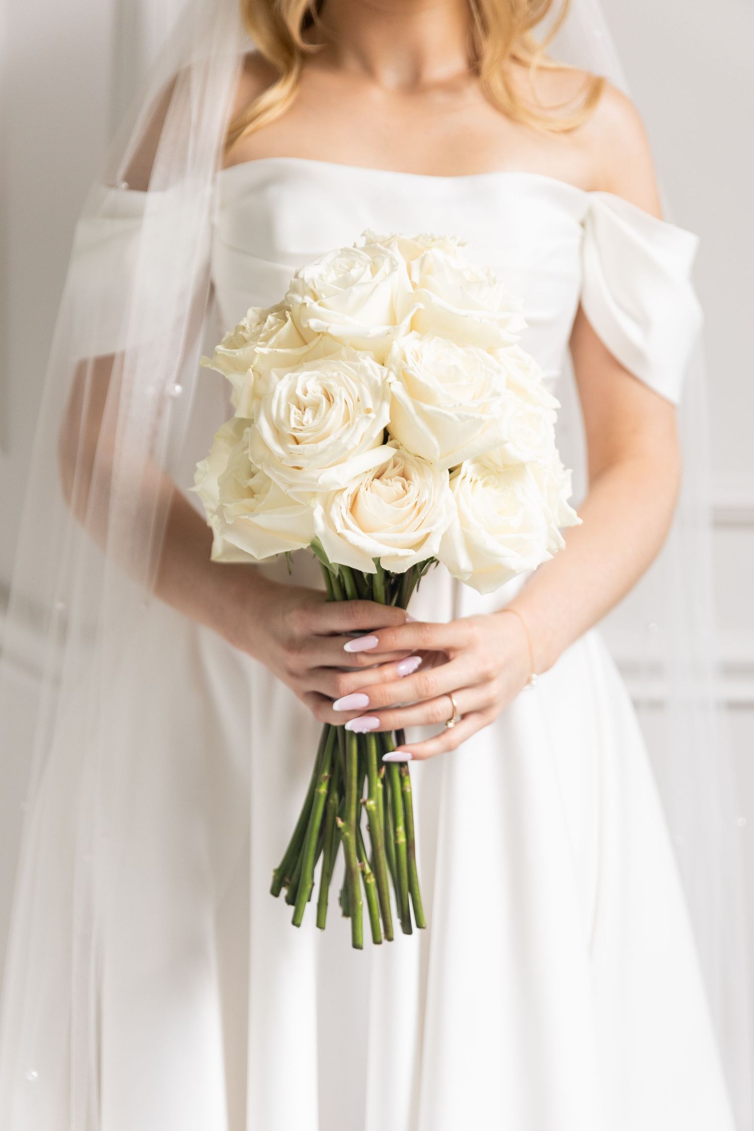 A series of elegant white bridal photos showing a bouquet of cream roses held against a flowing white wedding dress.