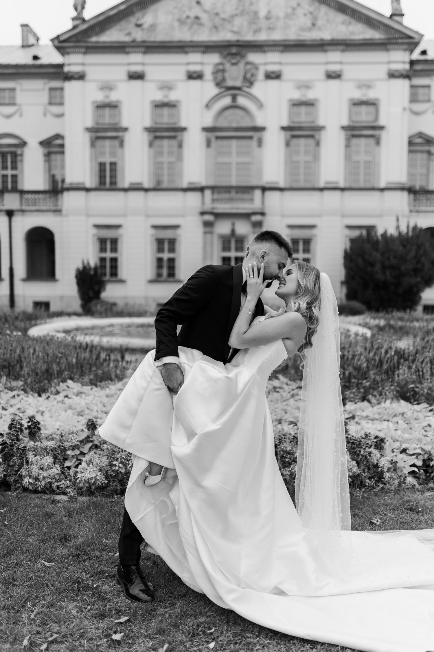 Romantic dip kiss pose in front of elegant historic building.