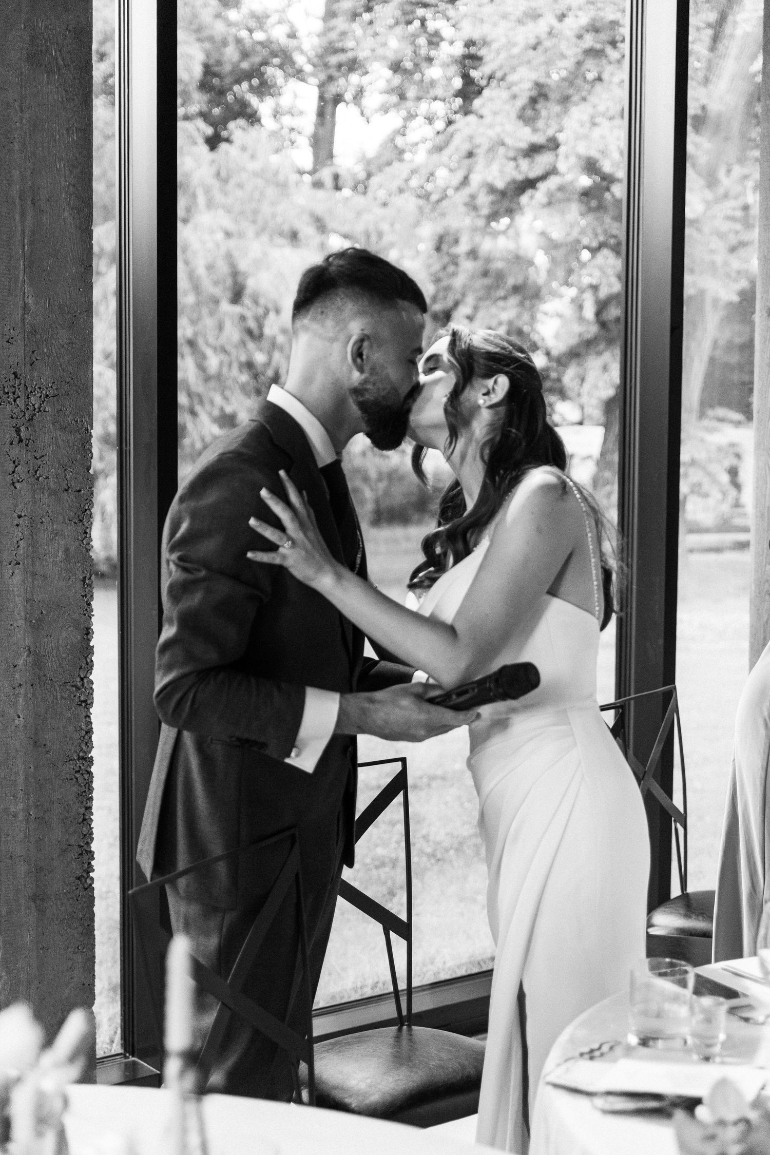 Black and white wedding photo sequence shows couple sharing first look moment in front of large windows.
