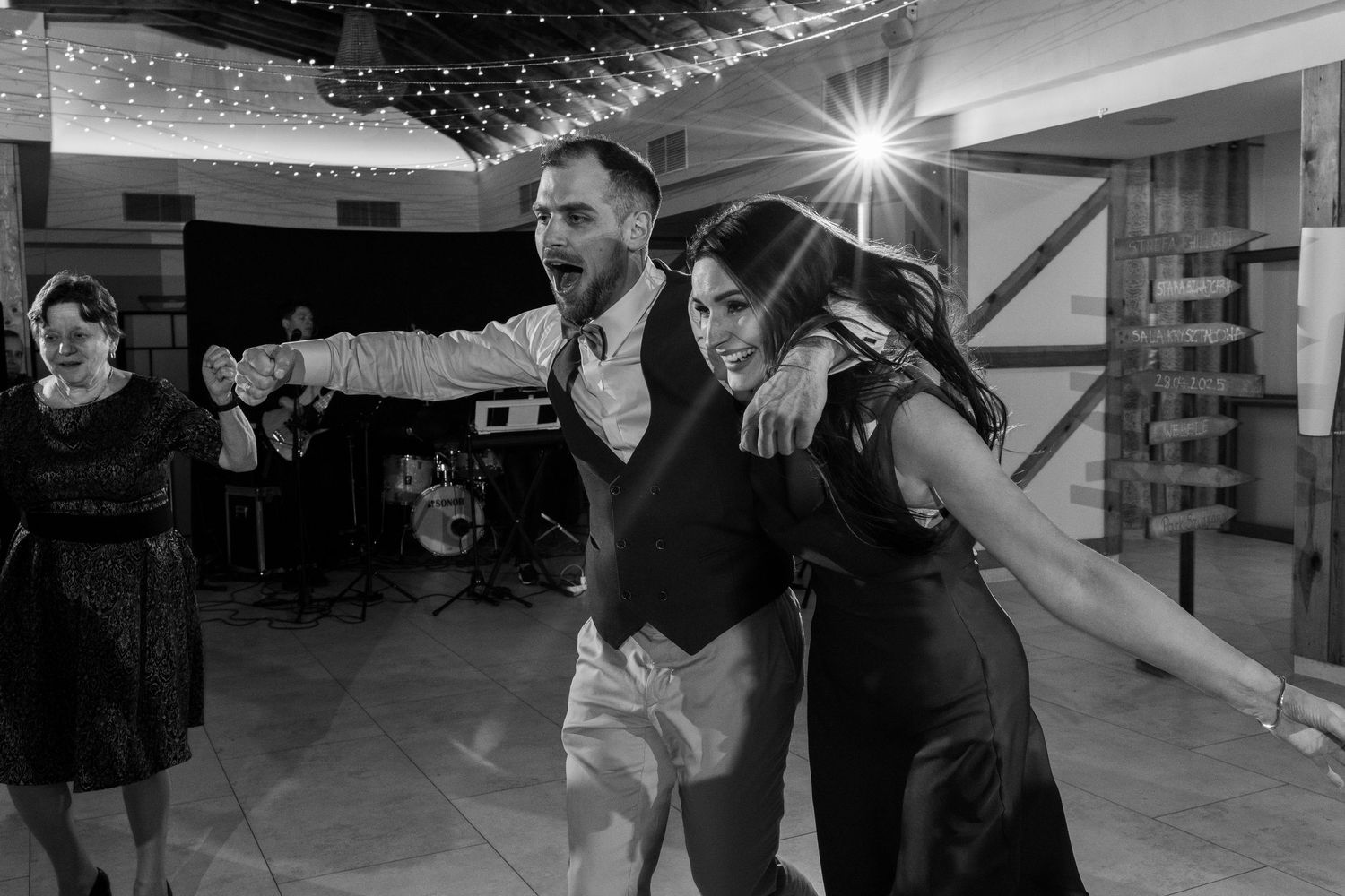 Black and white photo of a lively dance scene at a celebration with dancers having fun on the dance floor.