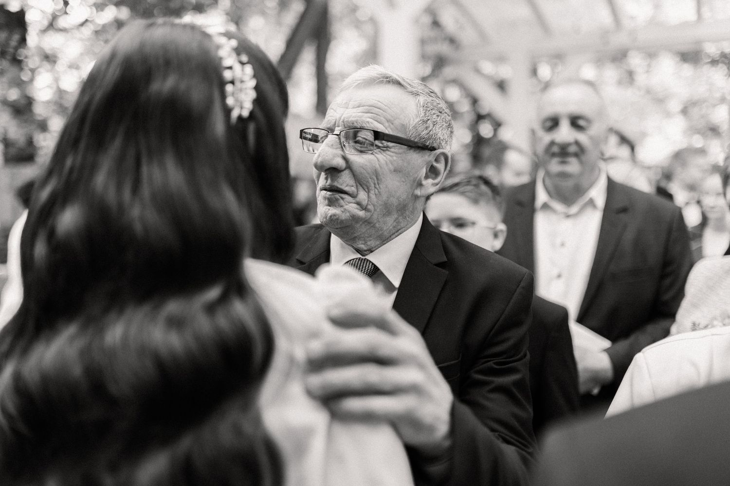 Black and white photo of people dancing at a wedding reception, captured in an intimate candid moment.