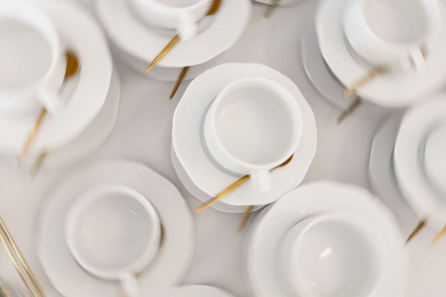 White disposable paper coffee cups with brown lids arranged in neat rows on a light gray surface.