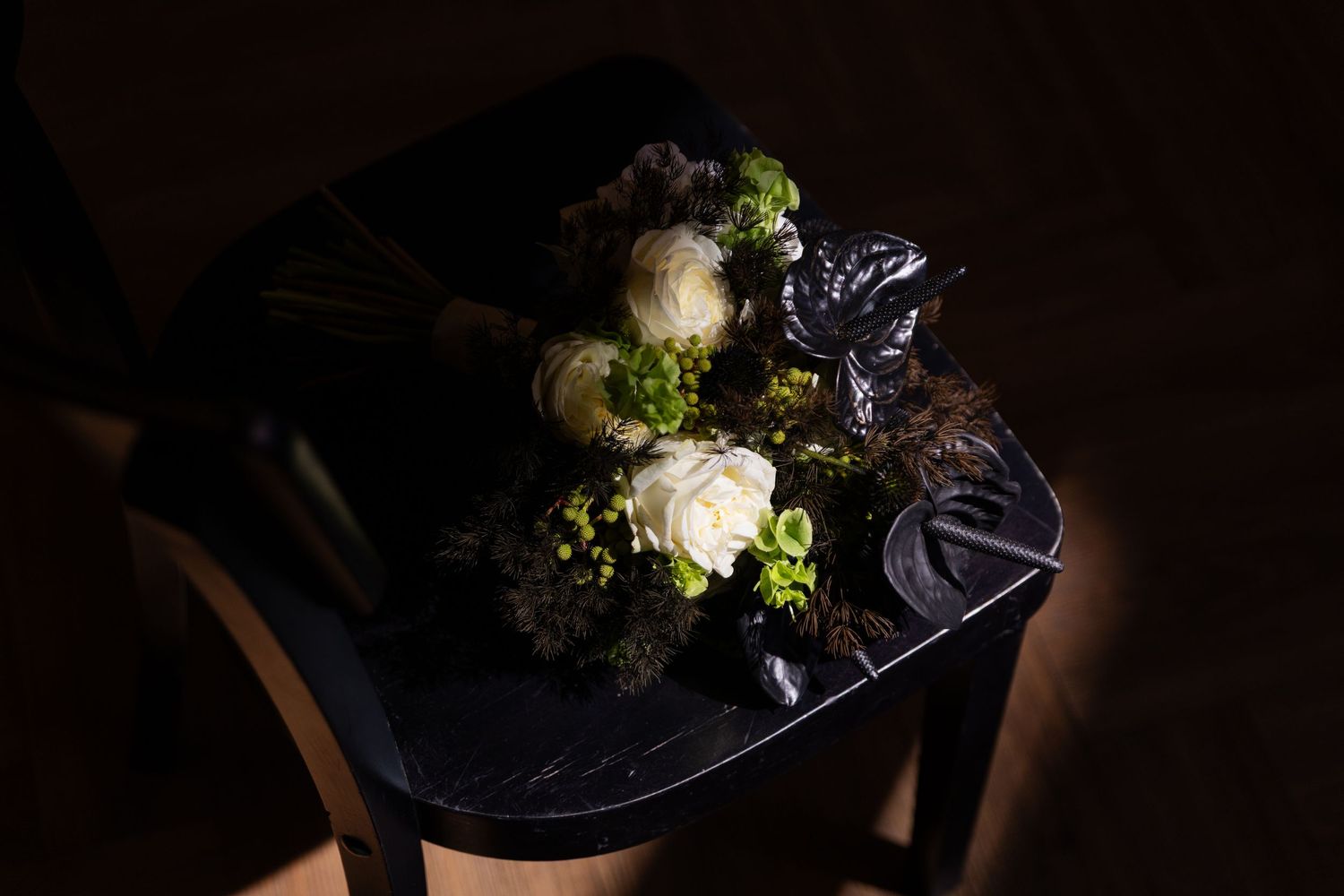 Dark moody food photography of broccoli florets and other ingredients on a black surface with dramatic lighting.