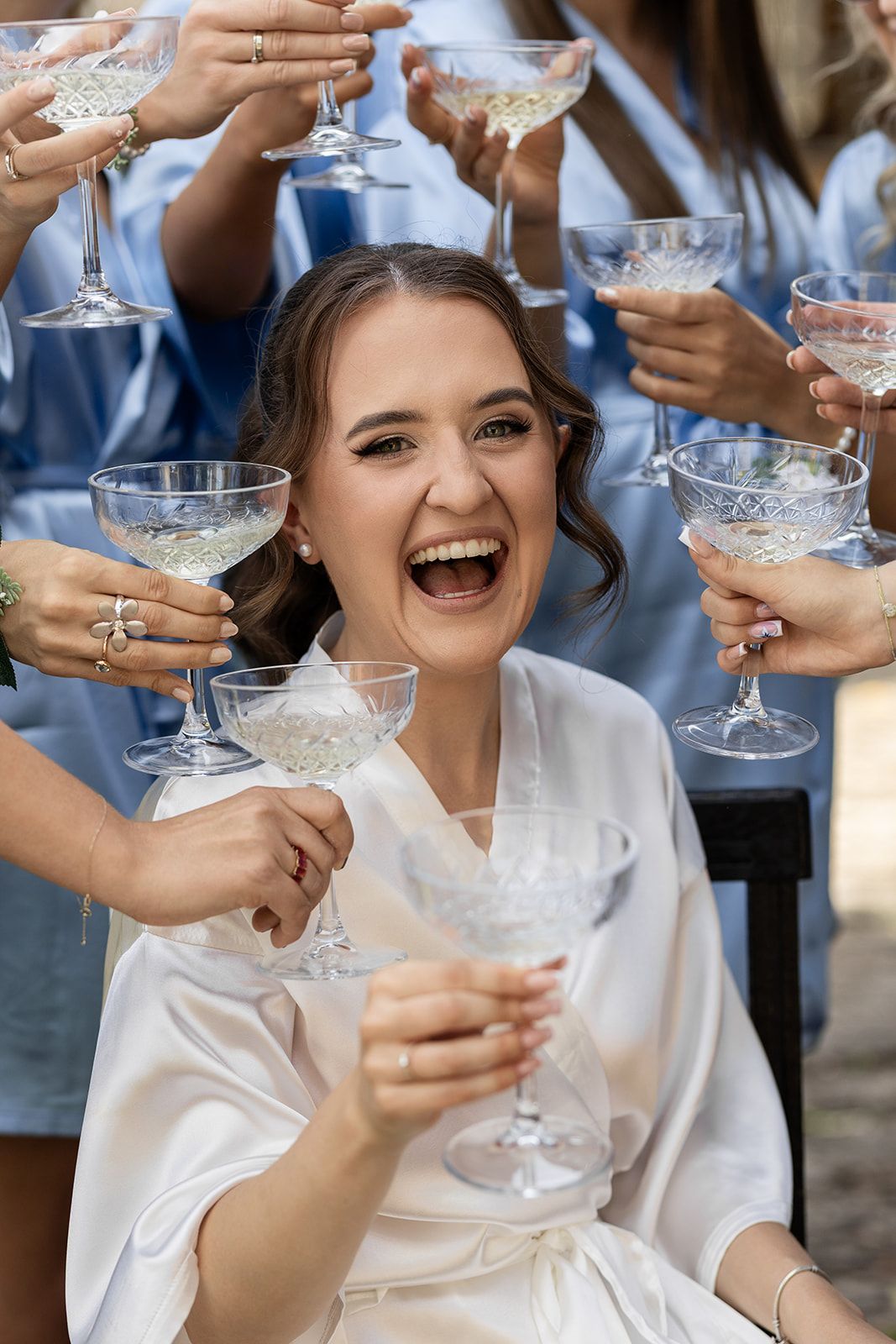 Wedding party toasting with champagne glasses during pre-ceremony preparations.