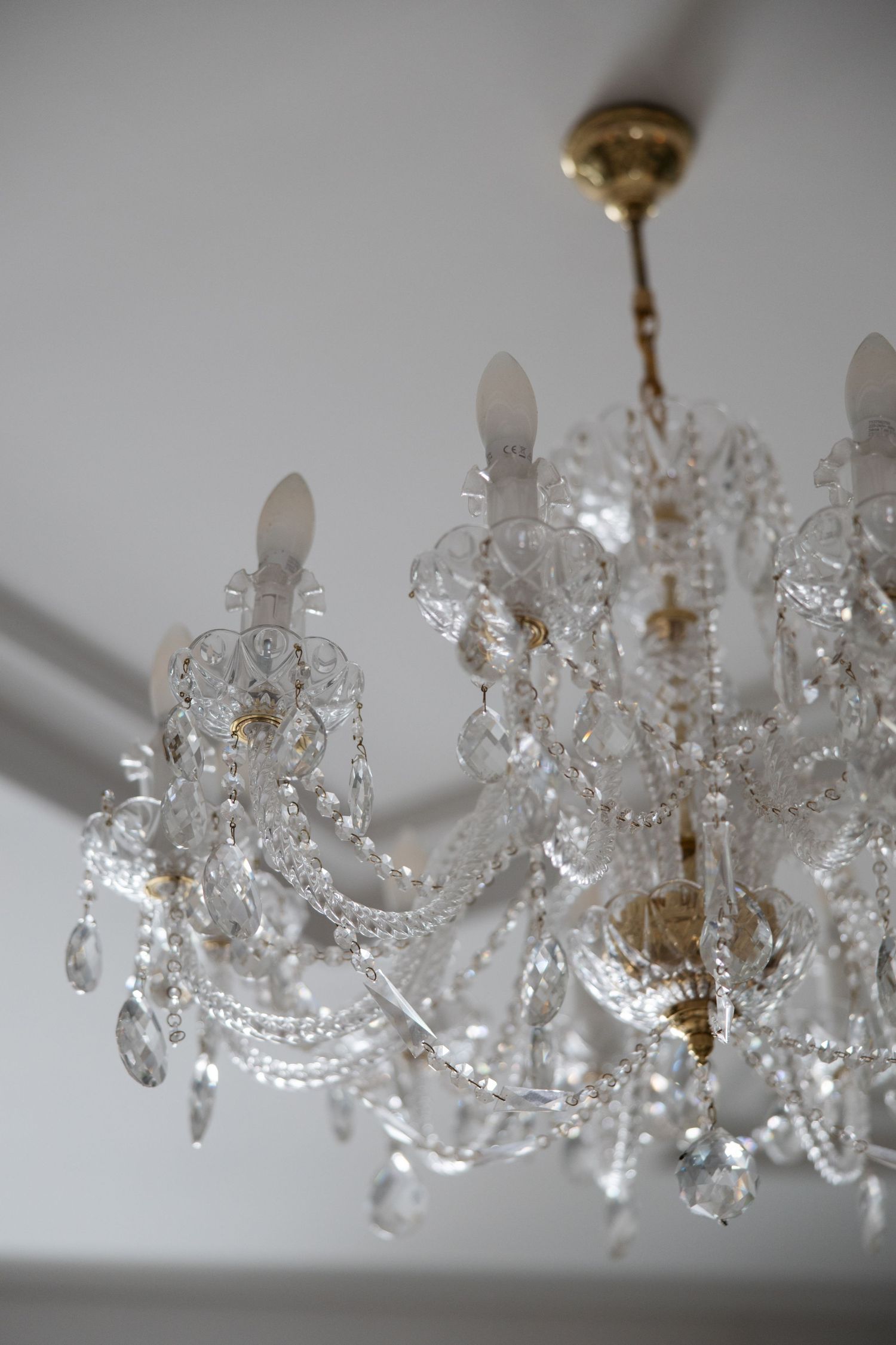 Elegant crystal chandelier with candle-style lights and gold accents hanging from a white ceiling.