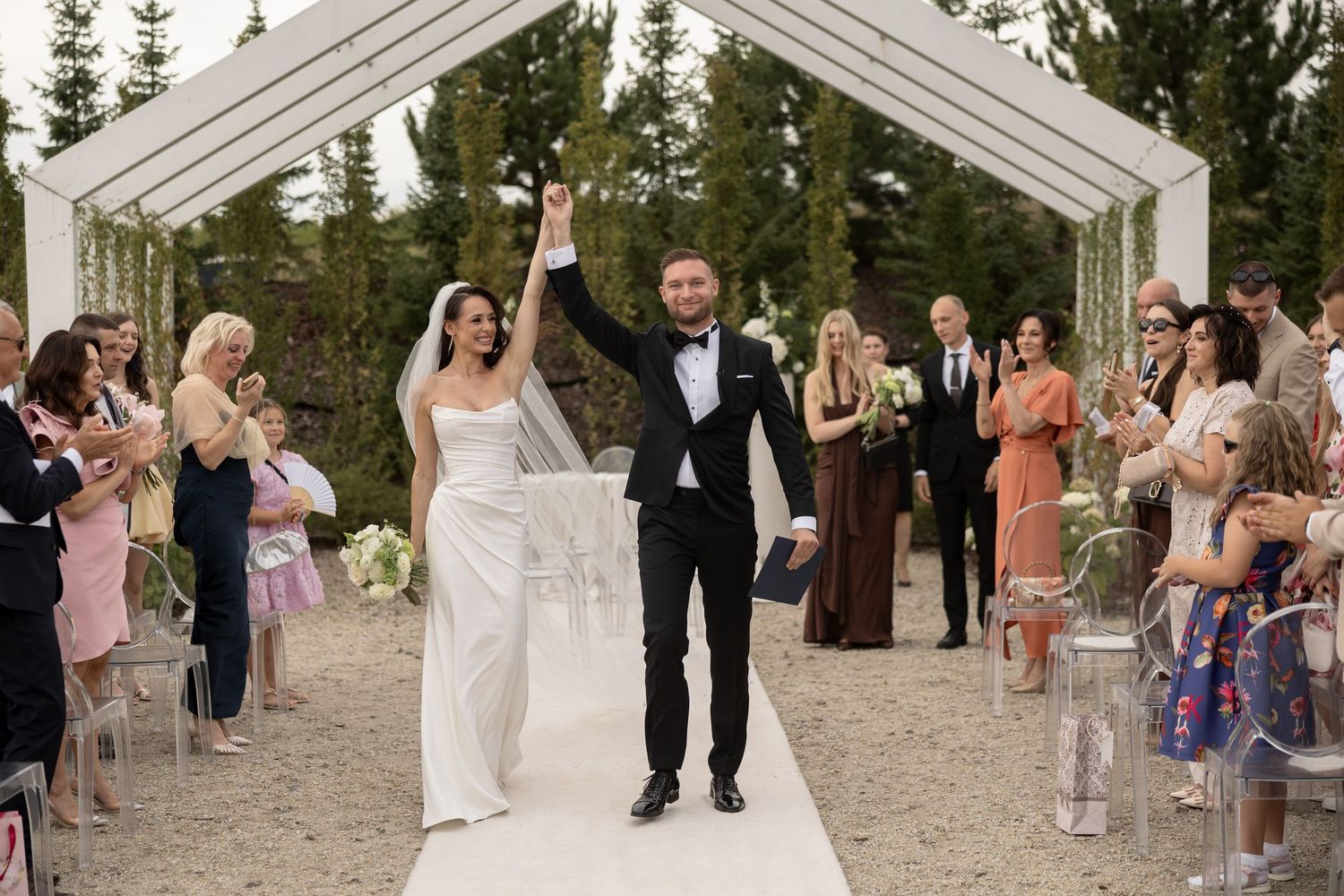 Bride and groom celebrate walking down the aisle after wedding ceremony outdoors.