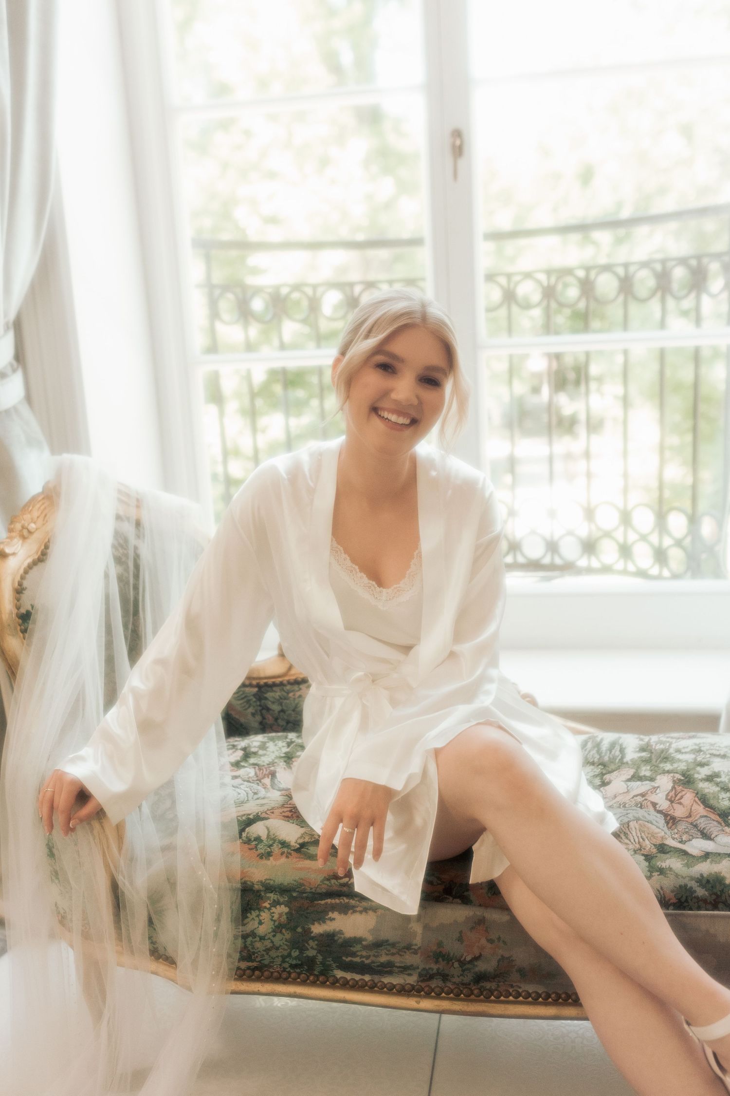 A series of boudoir photos showing someone in white silk robe lounging on an elegant daybed by a window.