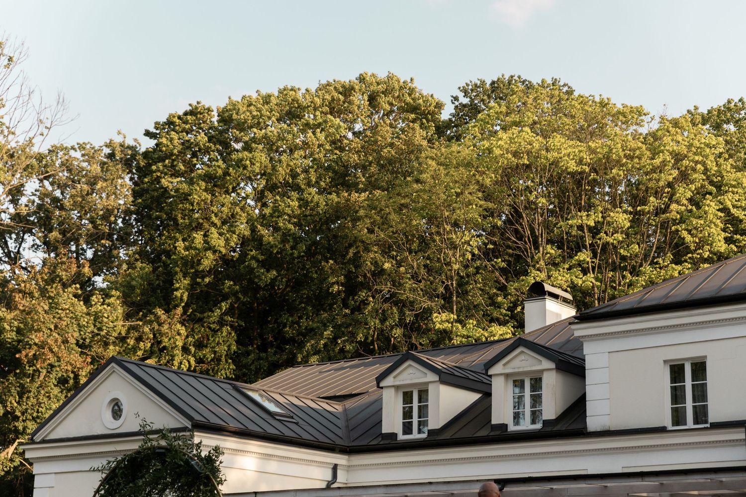 A panoramic view of residential homes with lush green trees in the background during a sunny day.
