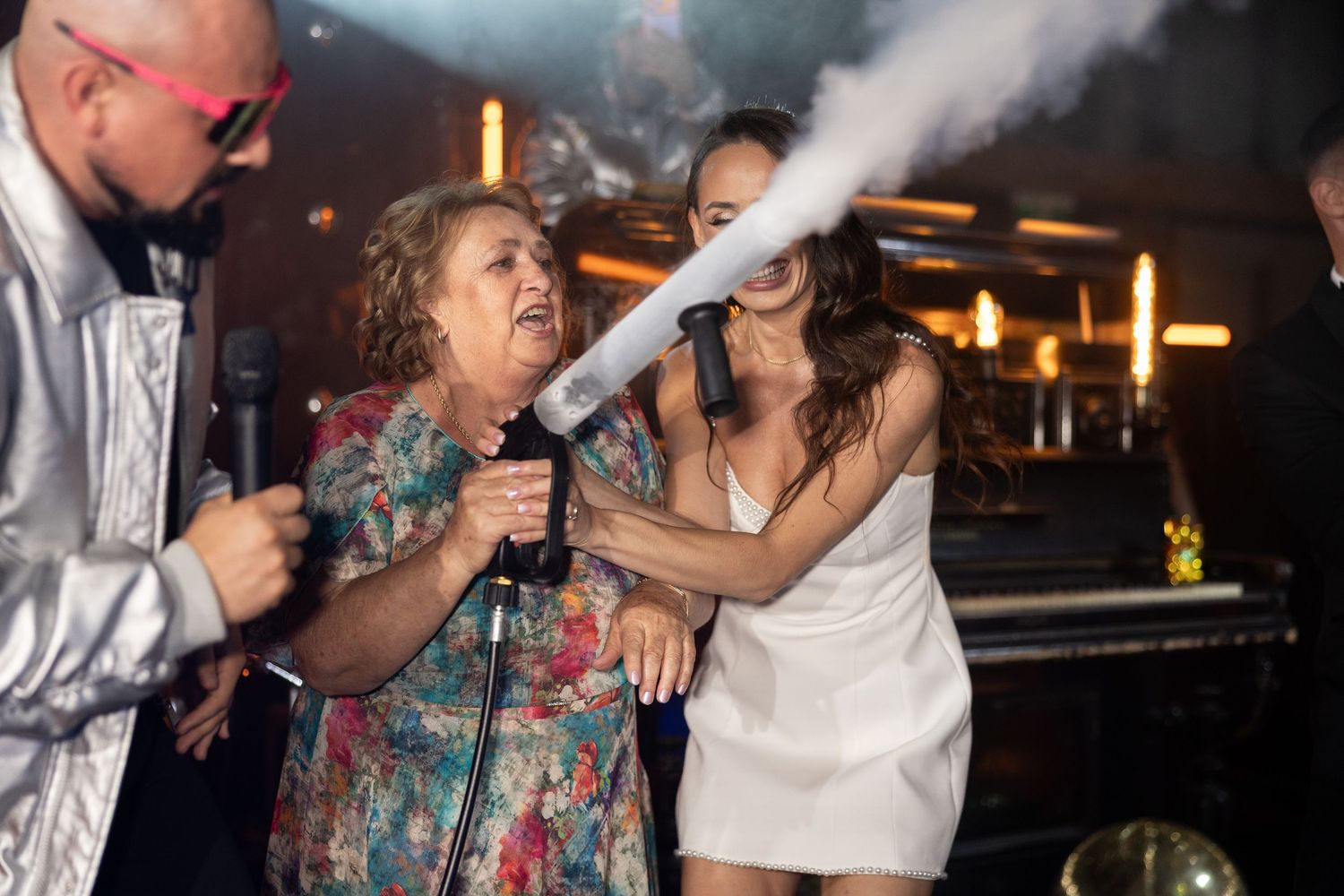 Women singing karaoke at a lively nightclub party with smoke effects and festive atmosphere.