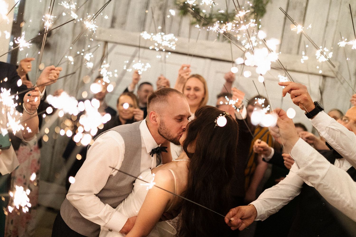 A couple shares their first dance as newlyweds while guests cheer and throw snowflake confetti at a winter wedding reception.