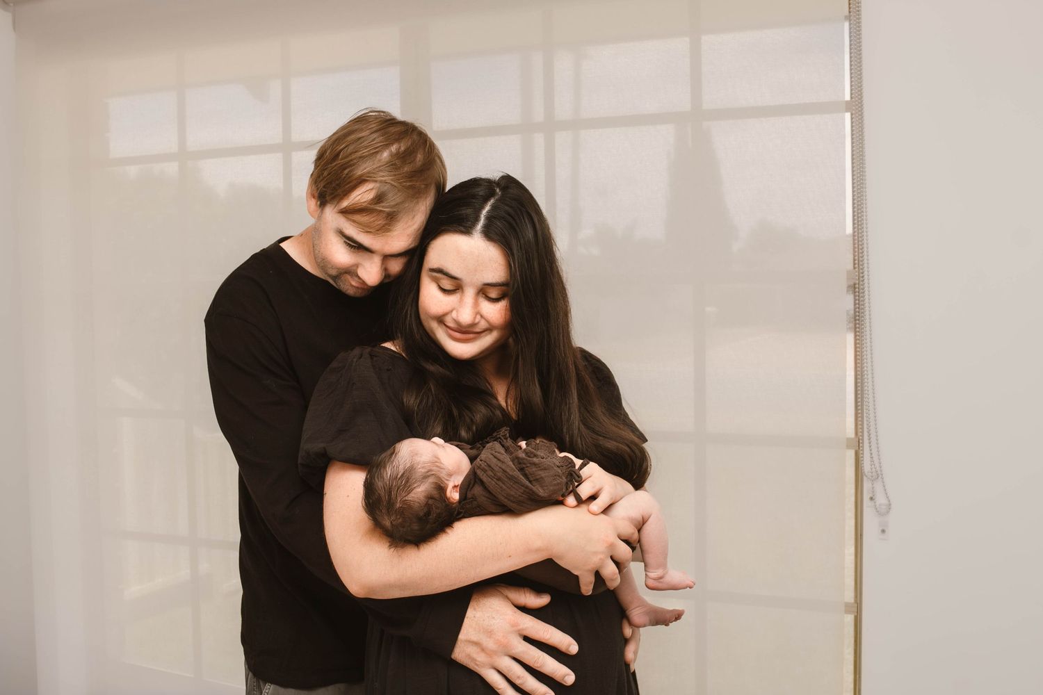 New parents hold their sleeping infant while sharing intimate moments together.