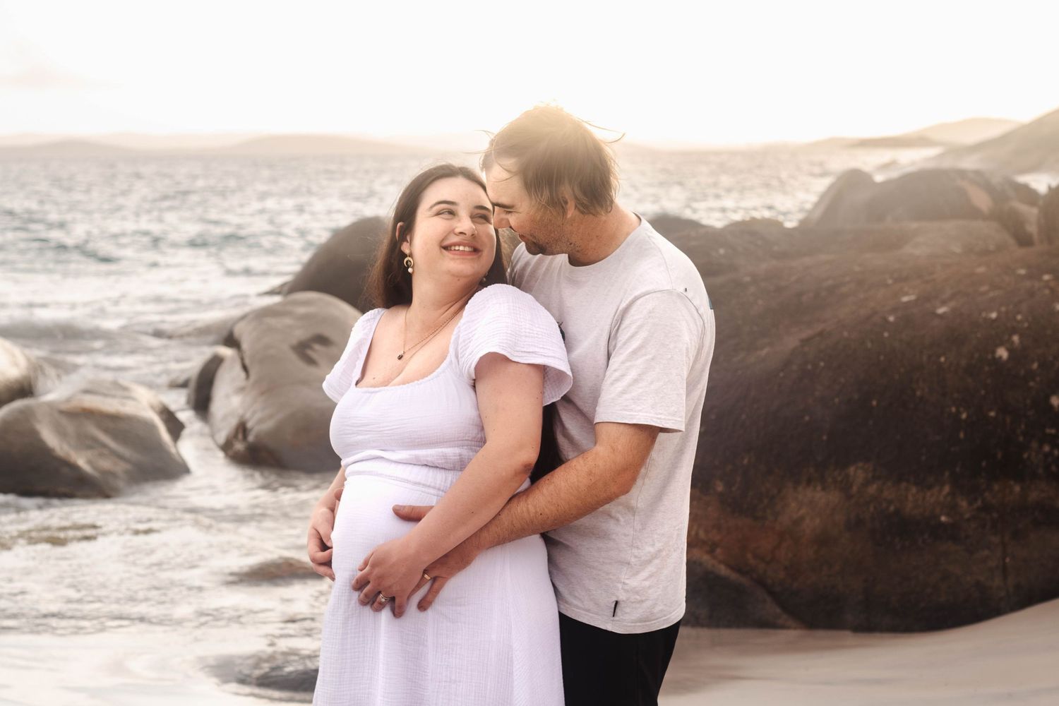 happy expecting couple posing in golden hour