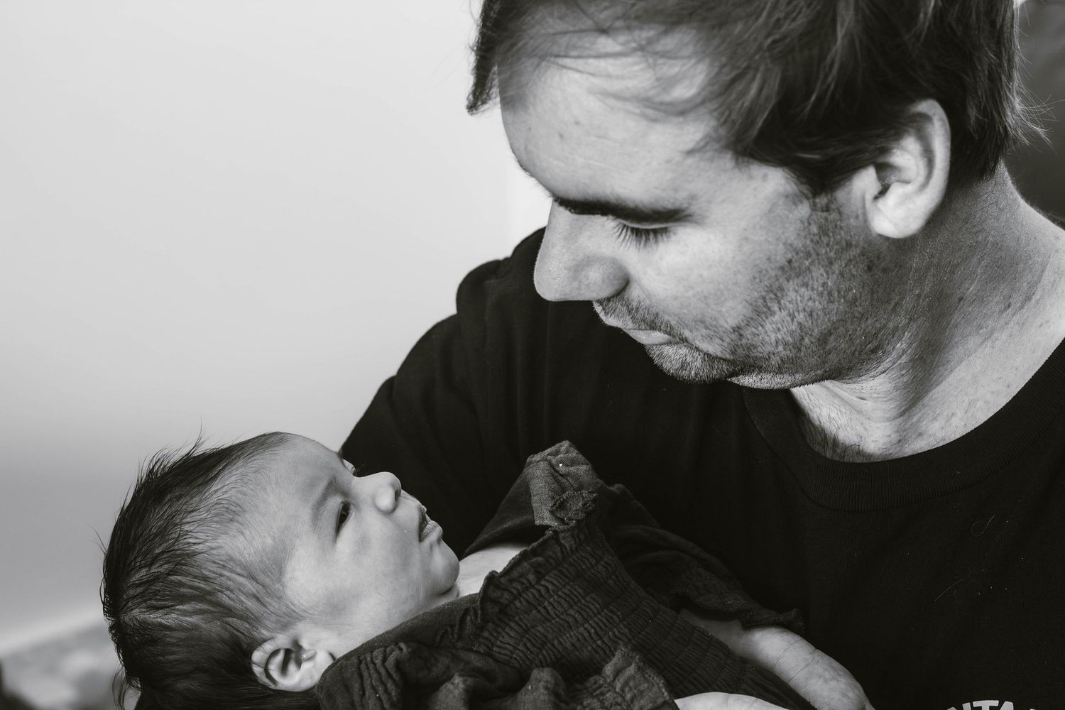 Black and white portrait of a parent gazing lovingly at their newborn baby.