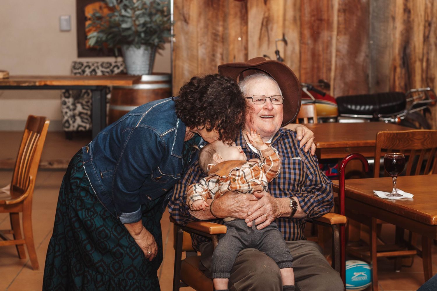 A warm moment of laughter and connection in a rustic wooden interior with plaid patterns and cozy seating.