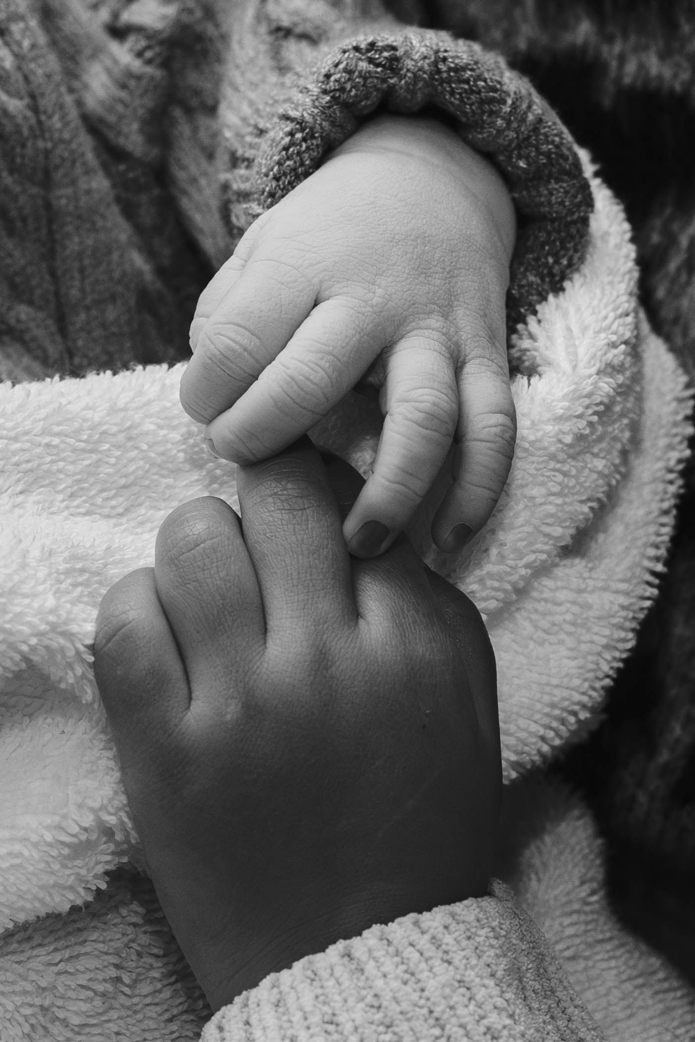newborn holding toddler siblings hand black and white birth photography