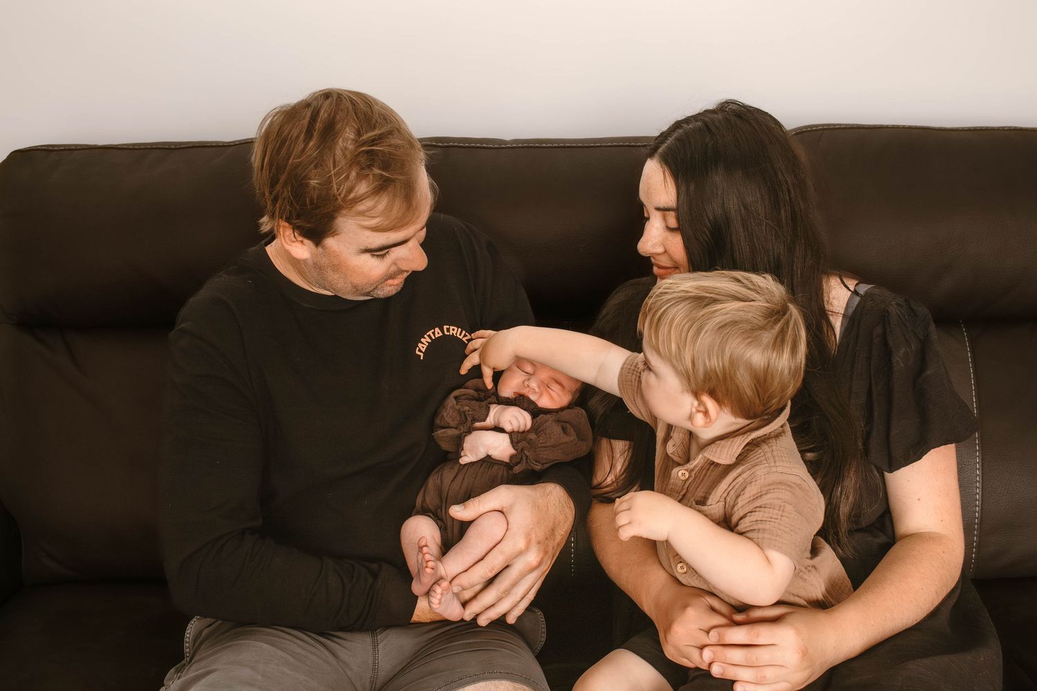 Intimate family moment shared on a leather couch with warm lighting.
