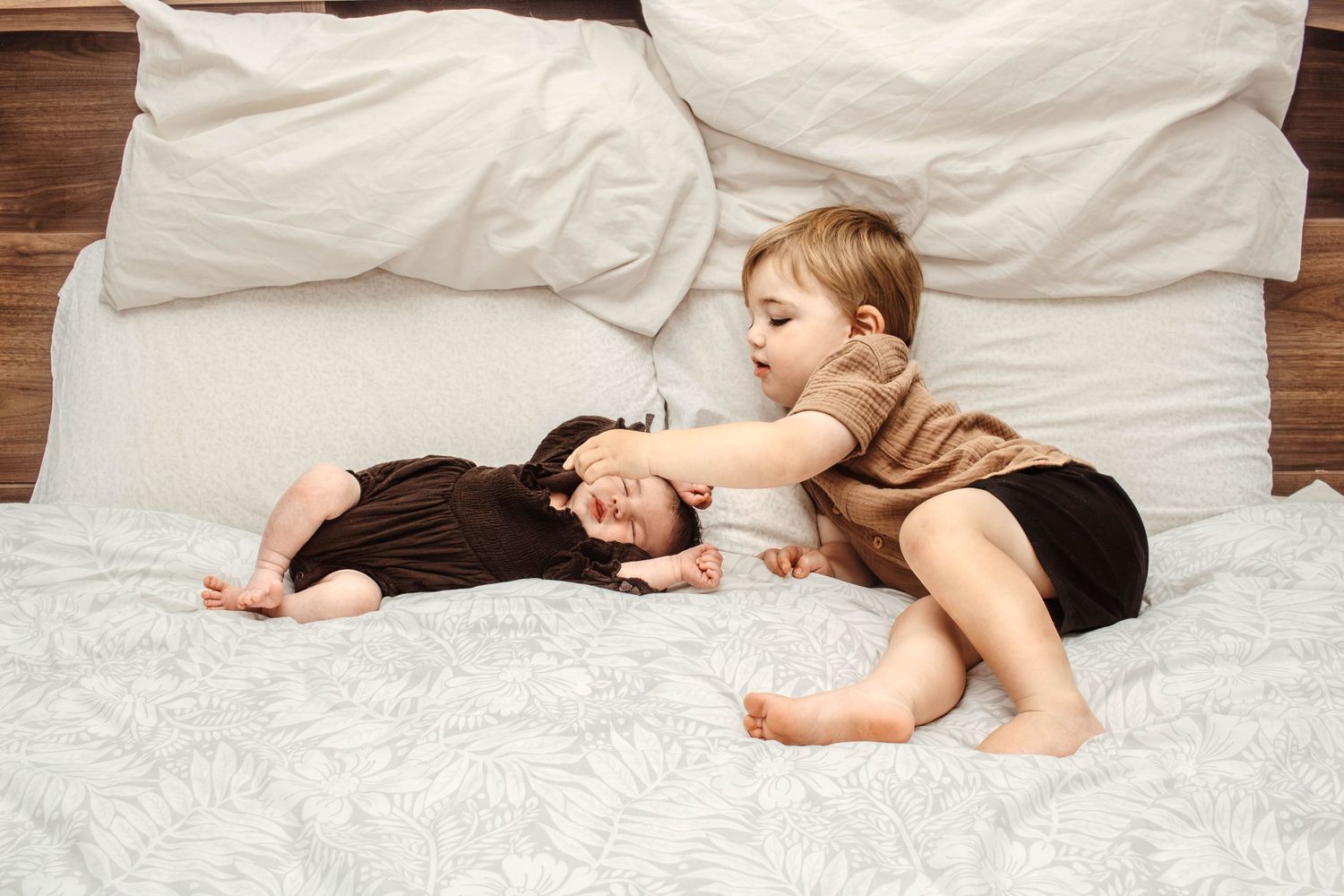 Two people resting peacefully together on a white bed with wooden frame.