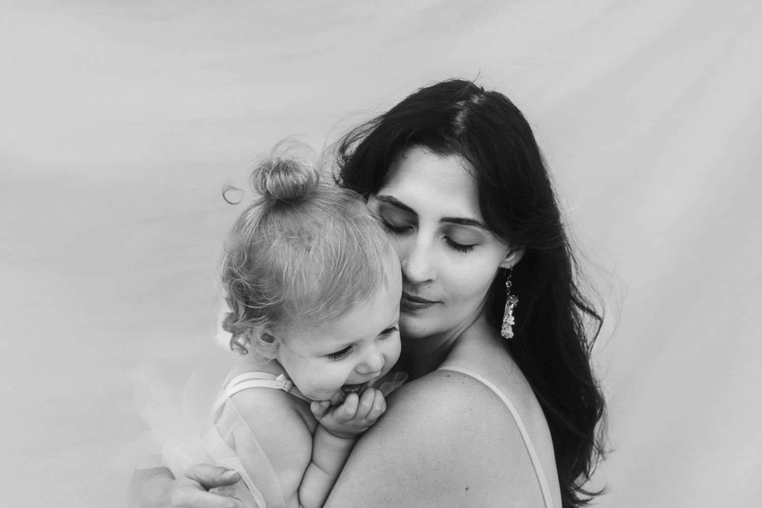 black and white image of mother cuddles a laughing toddler