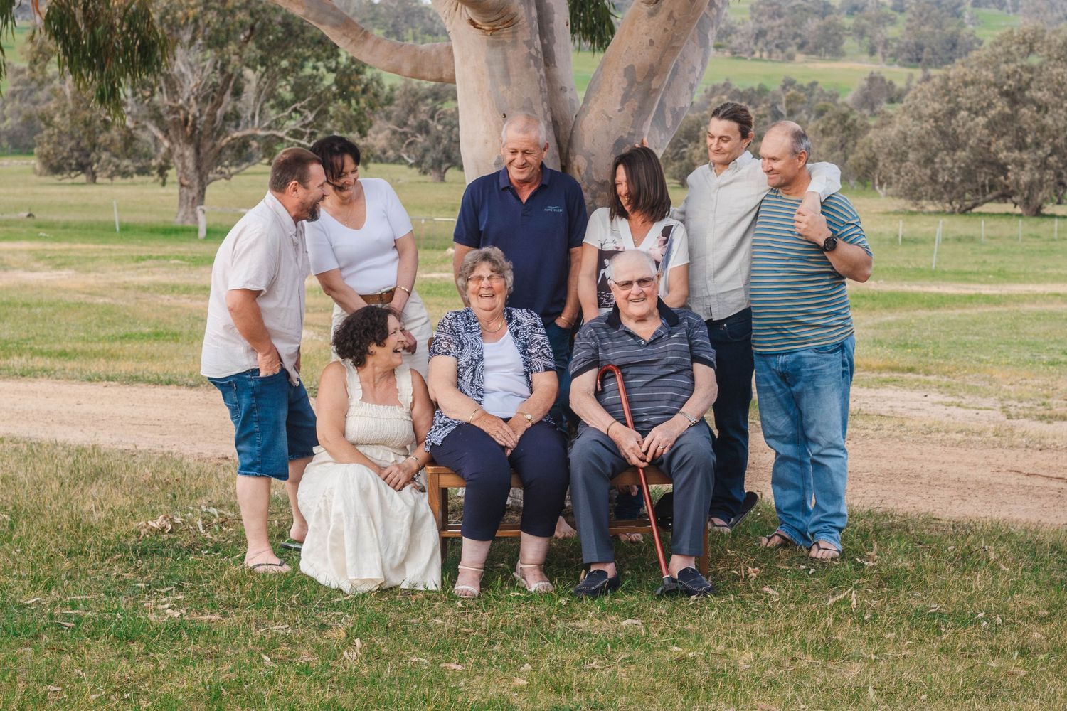 Extended family gathering for outdoor portrait under majestic eucalyptus tree.