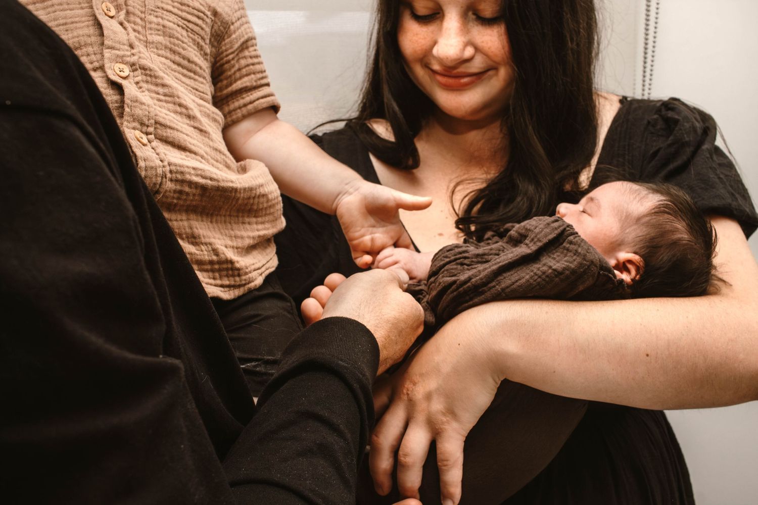 Tender moment captured as parents interact with their infant in warm lighting.