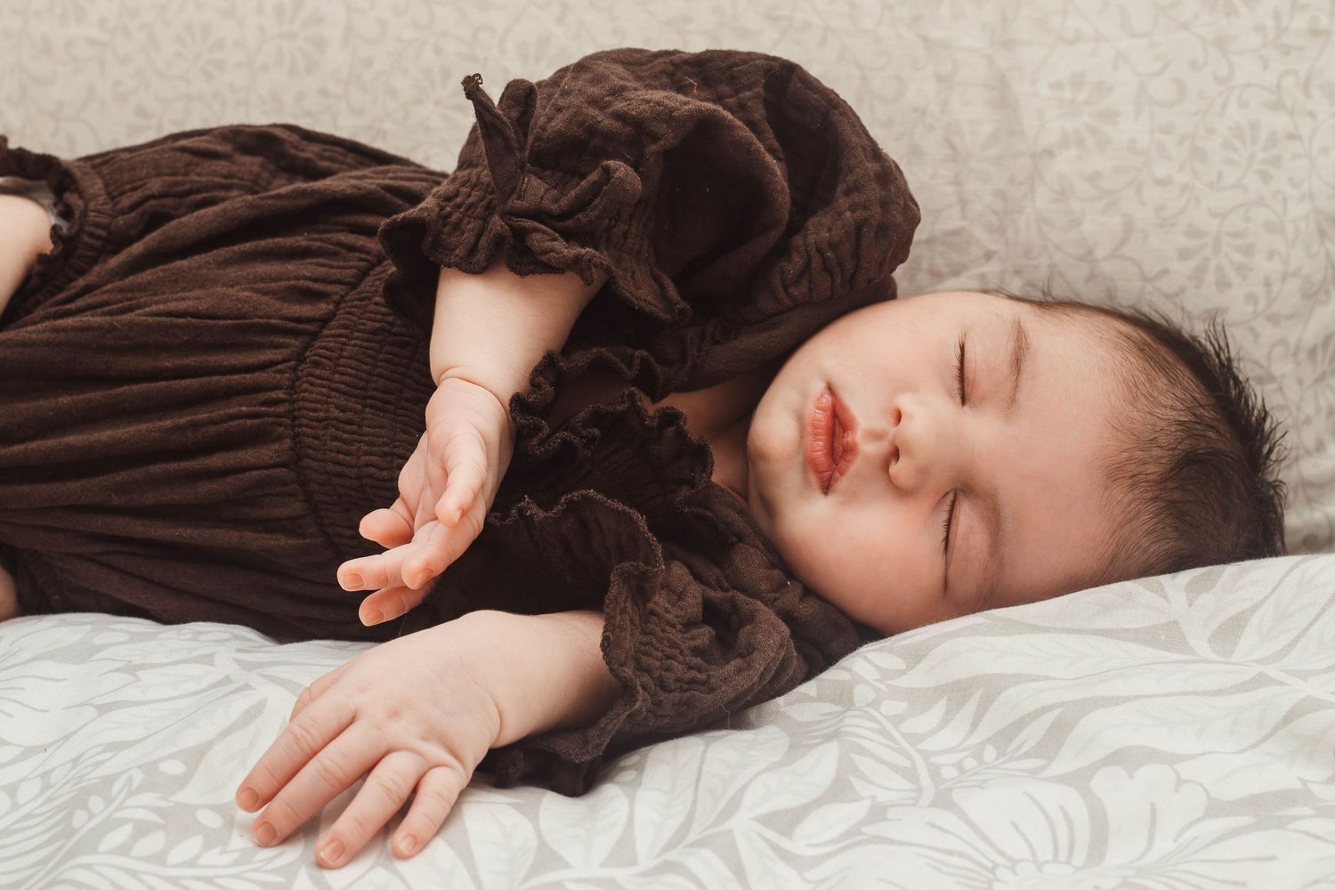 Sleeping figure in brown ruffled dress against white bedding.