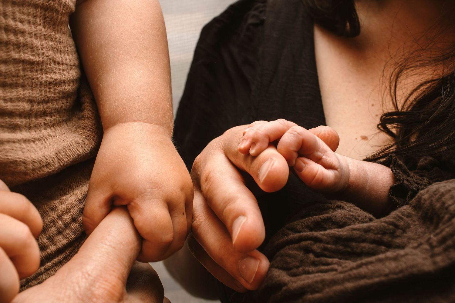 Close-up photograph of family hands touching in warm, golden tones.