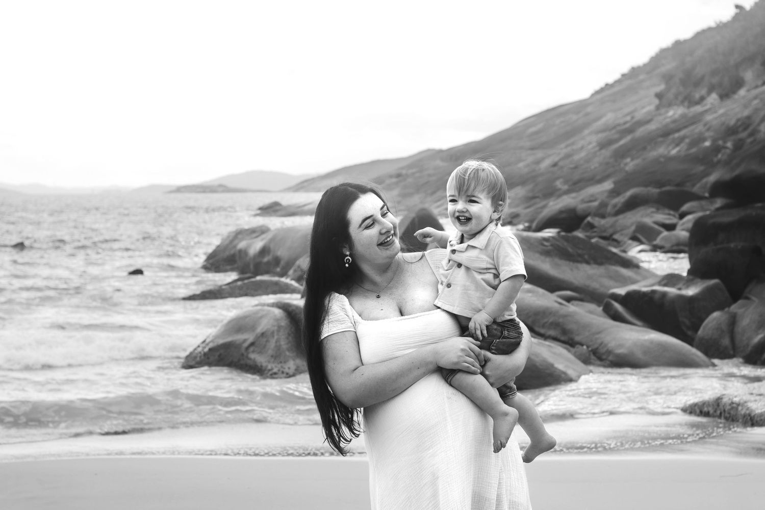 Peaceful beachside portrait session with waves crashing against rocky shore in the background.