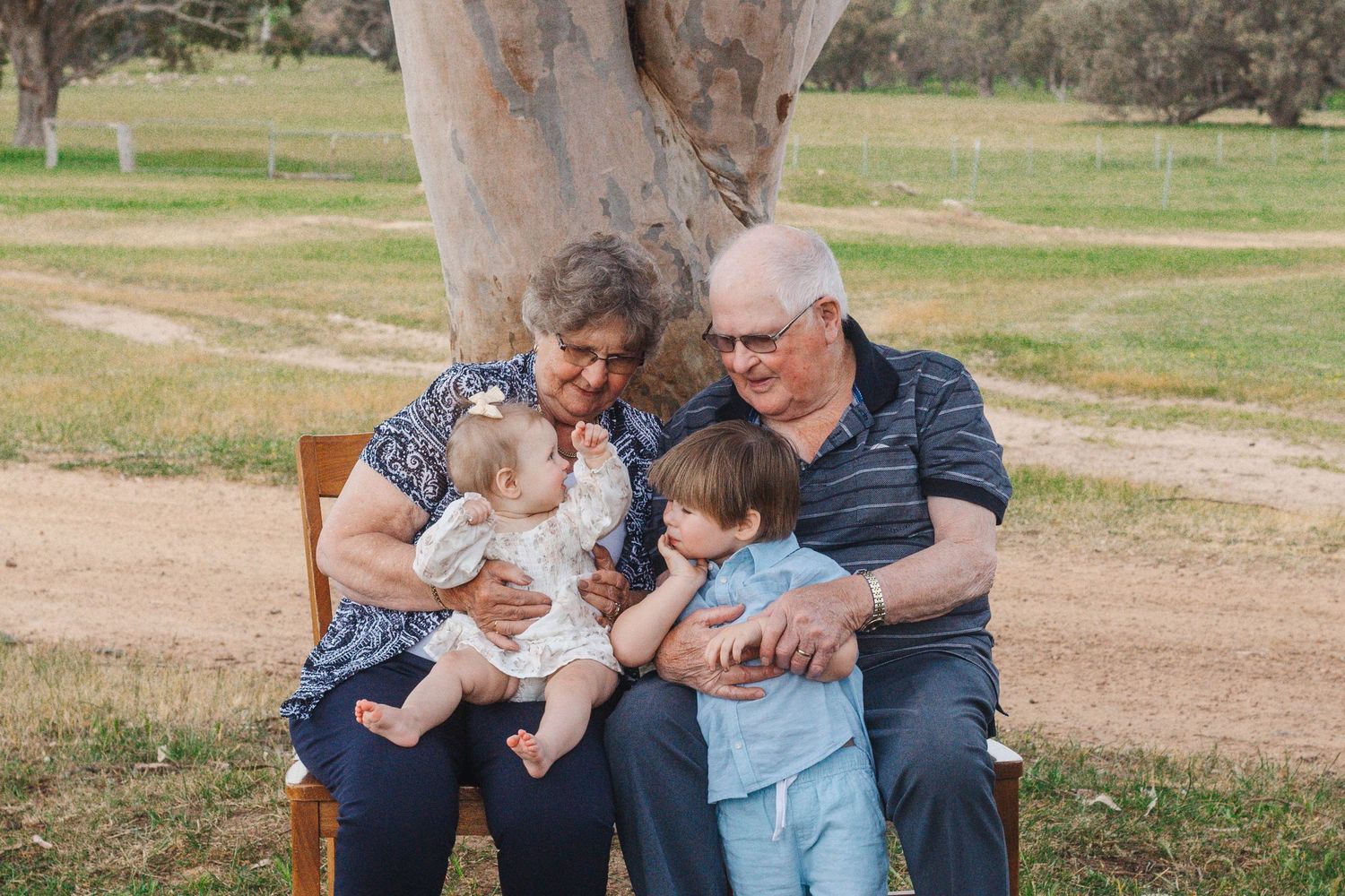 Loving family moment captured outdoors with children under an Australian gum tree.