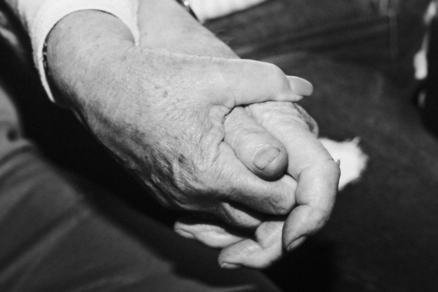 A black and white close-up of intertwined hands showing connection and intimacy.