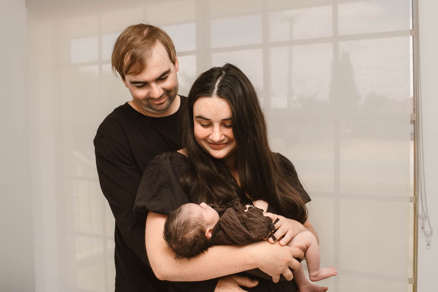 Parents share an intimate moment with their newborn baby in a warmly lit room.