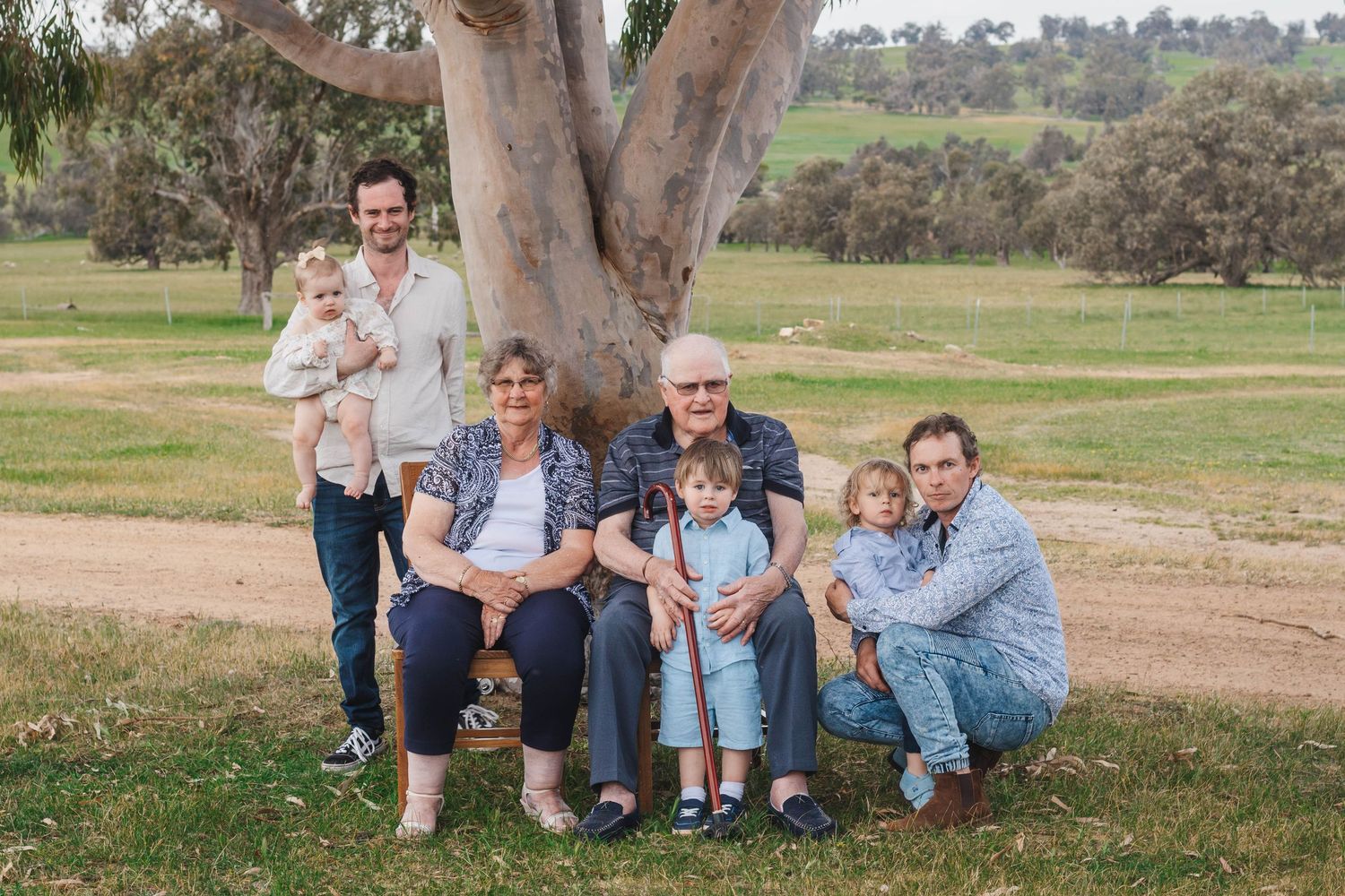 Multi-generational family poses together under a large eucalyptus tree in an Australian rural setting.