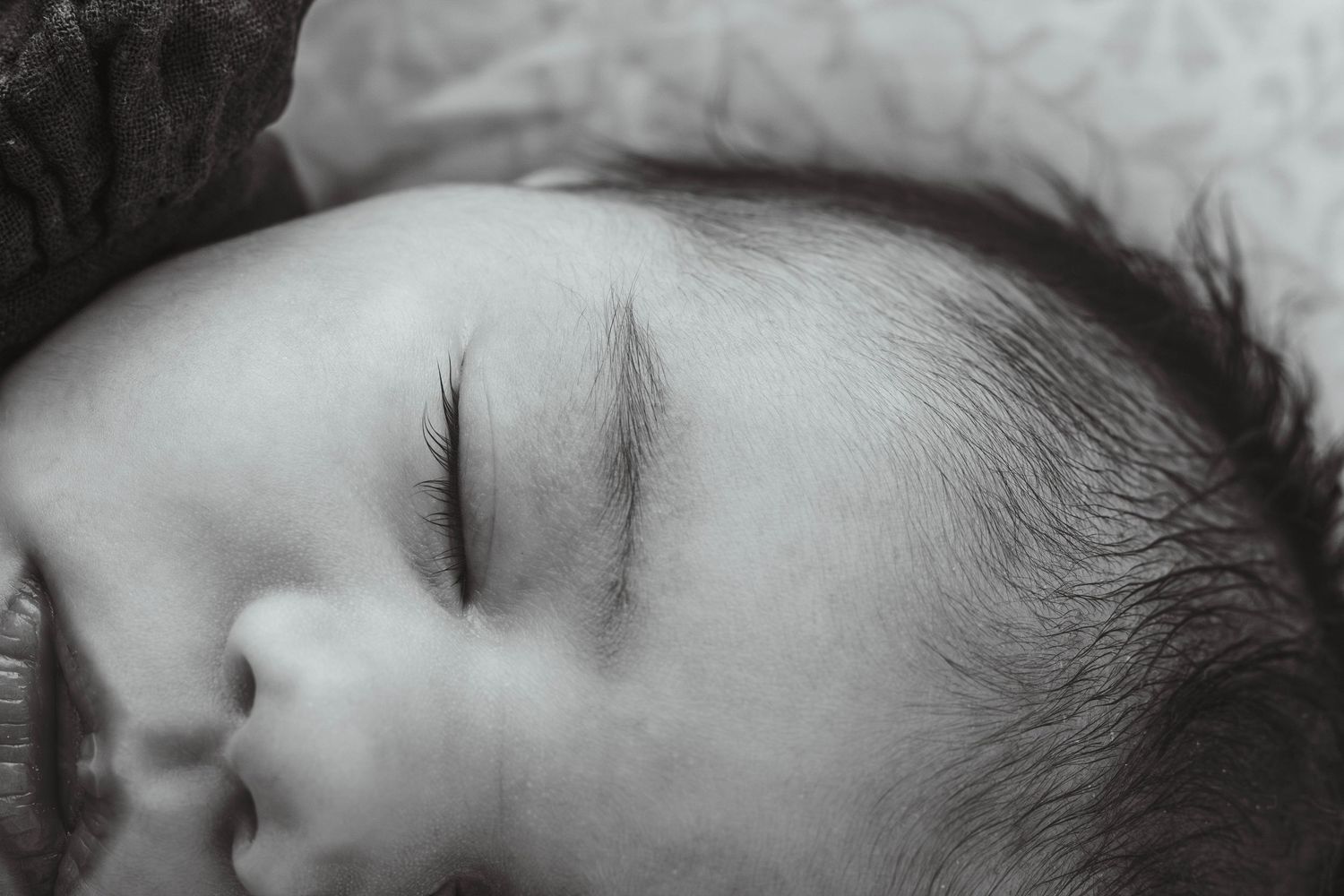 Black and white portrait of sleeping baby with soft facial features.