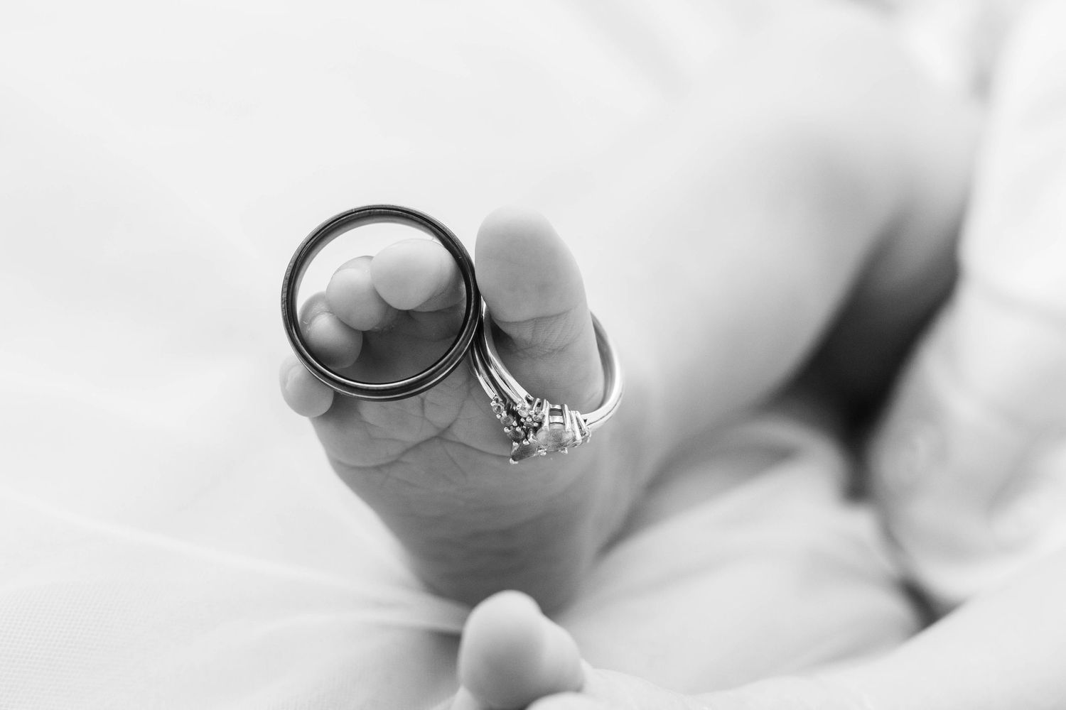 Artistic black and white macro shot of infant toes with jewelry.