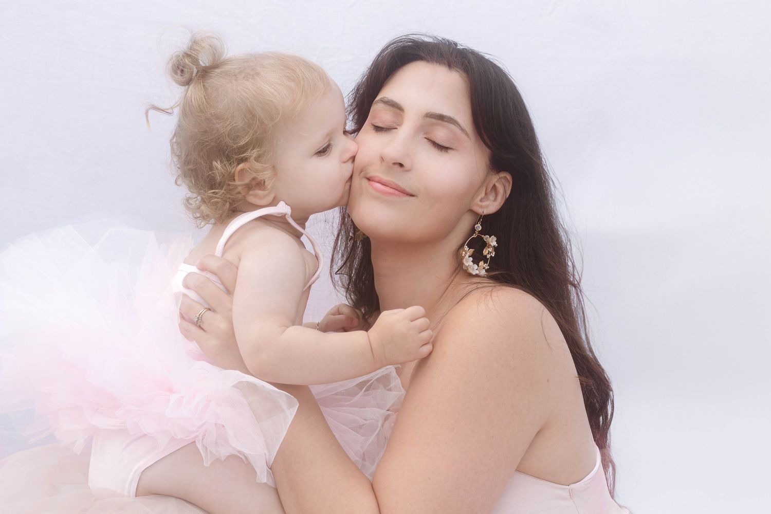 baby girl kisses mothers cheek